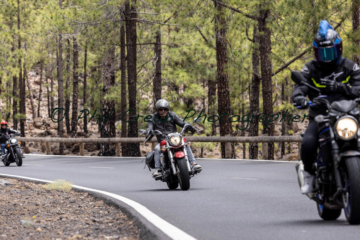 A group of people are riding motorcycles down a road.