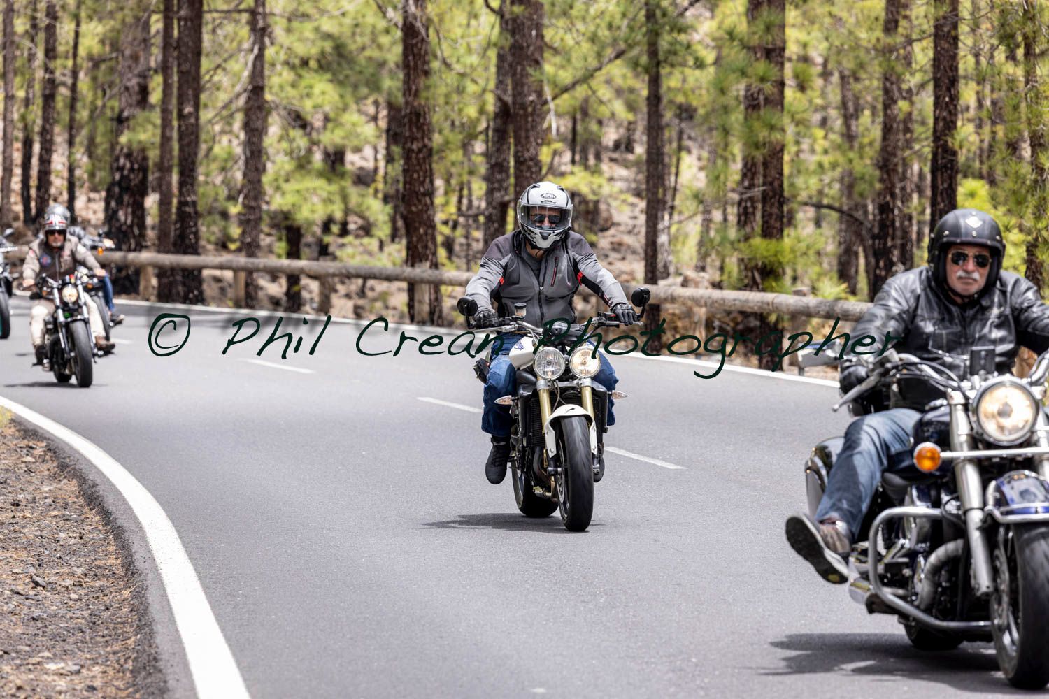 A group of men are riding motorcycles down a road