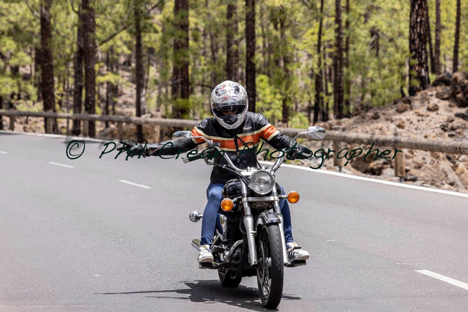 A man is riding a motorcycle down a road.