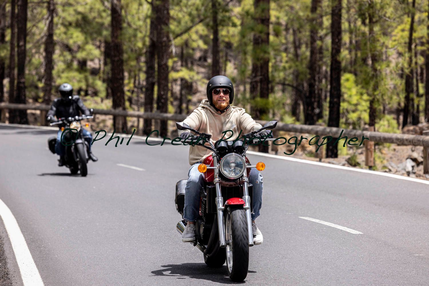 Two men are riding motorcycles down a road.