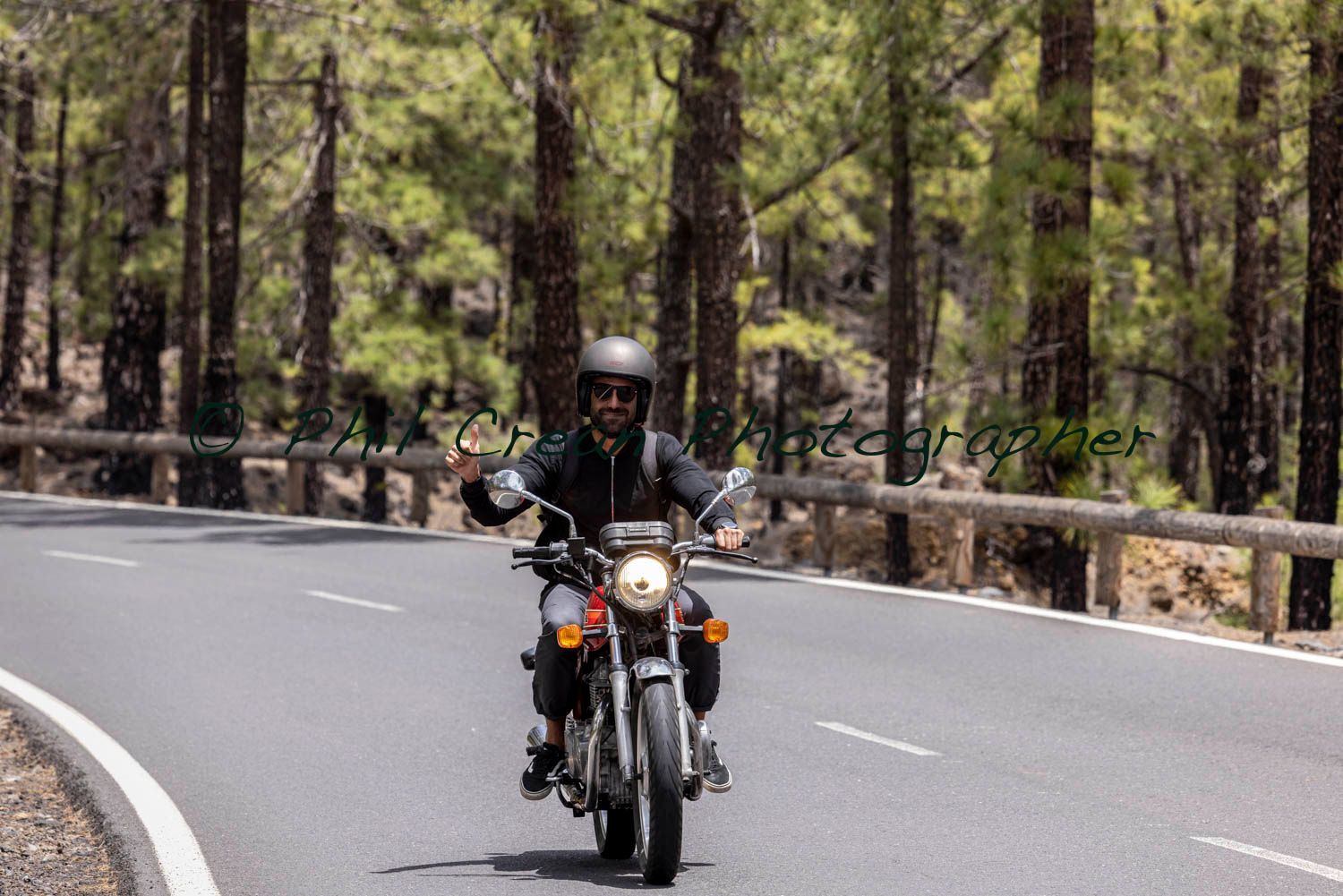 A man is riding a motorcycle down a curvy road.