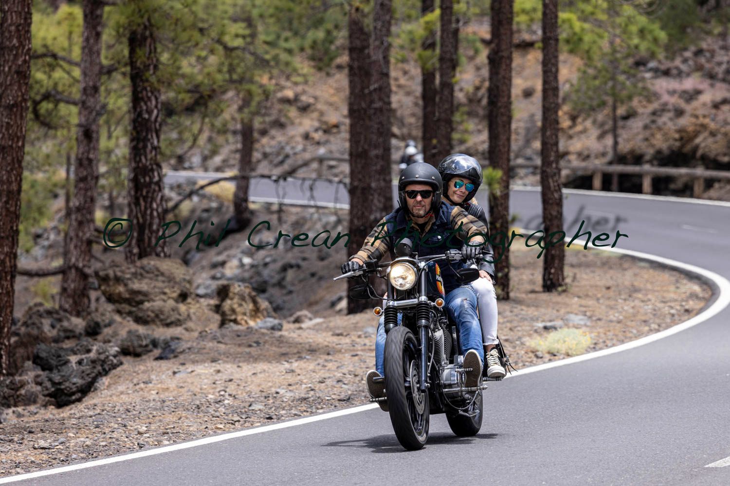 A man and a woman are riding a motorcycle down a curvy road.