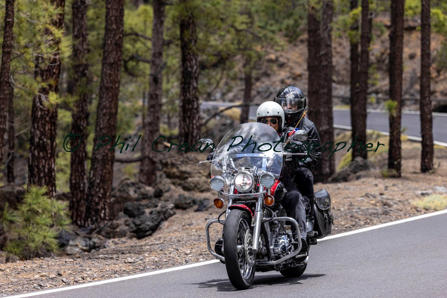 A couple of people are riding a motorcycle down a road.
