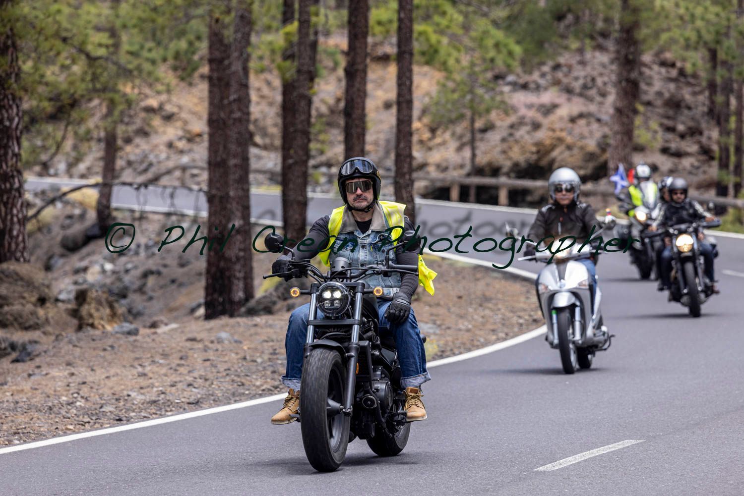A group of people are riding motorcycles down a road.