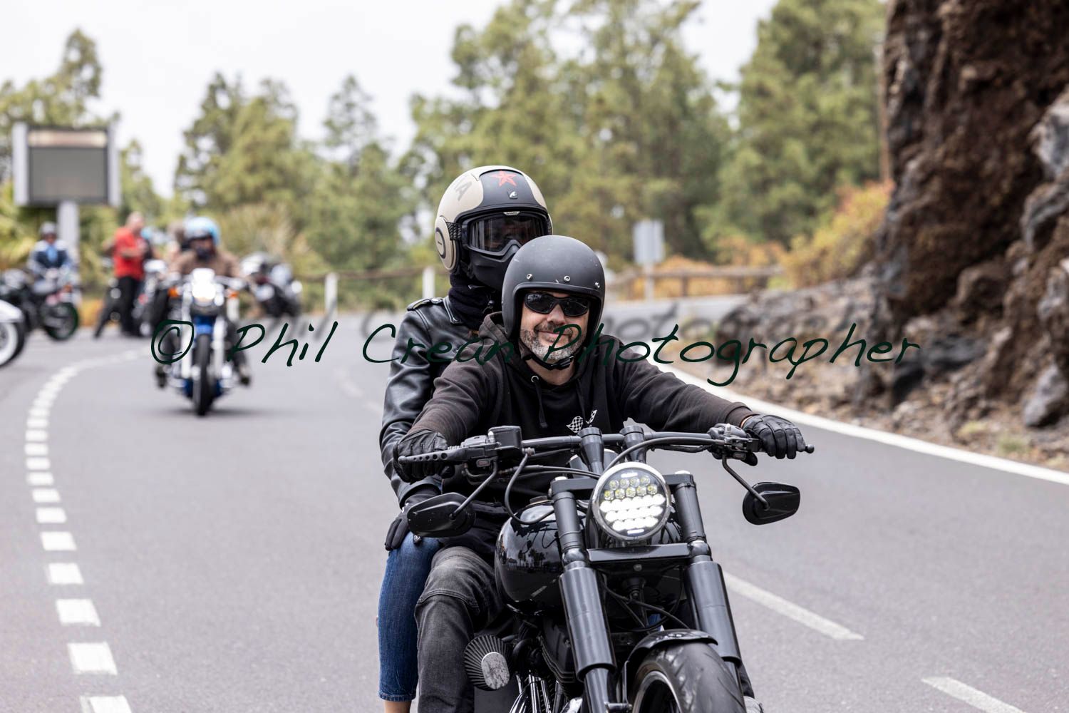 A man and a woman are riding a motorcycle down a road.