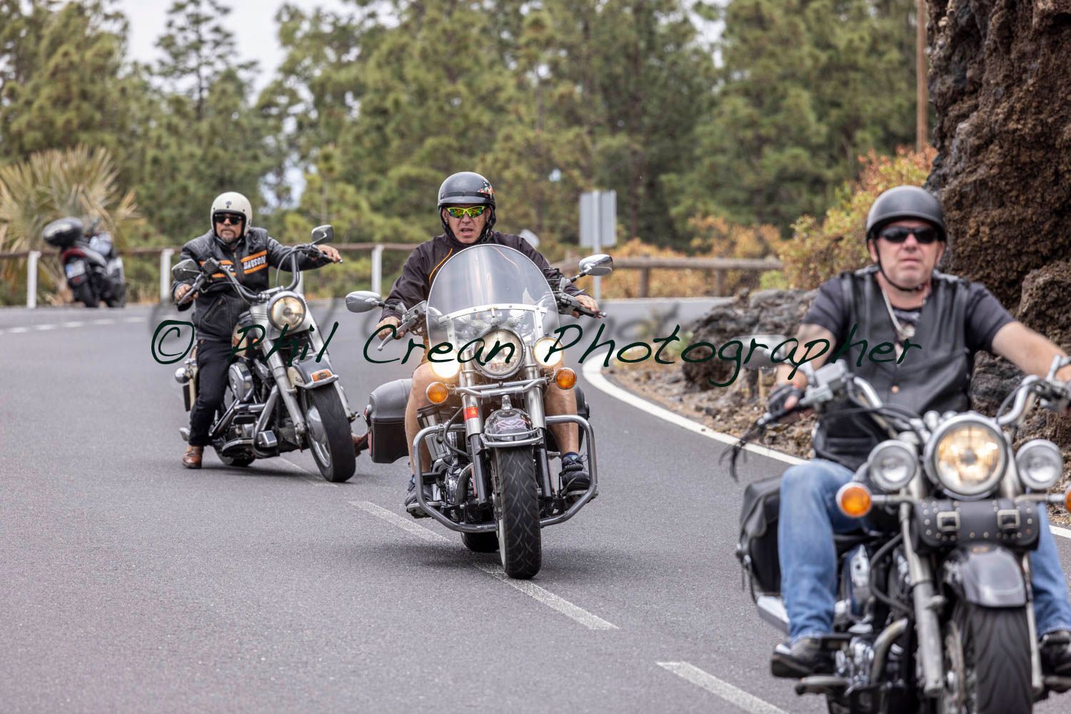 A group of men are riding motorcycles down a road.