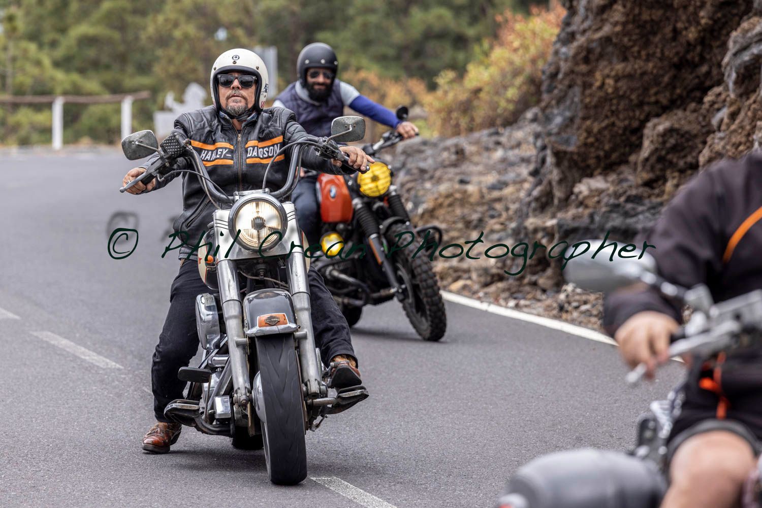 A group of men are riding motorcycles down a road.
