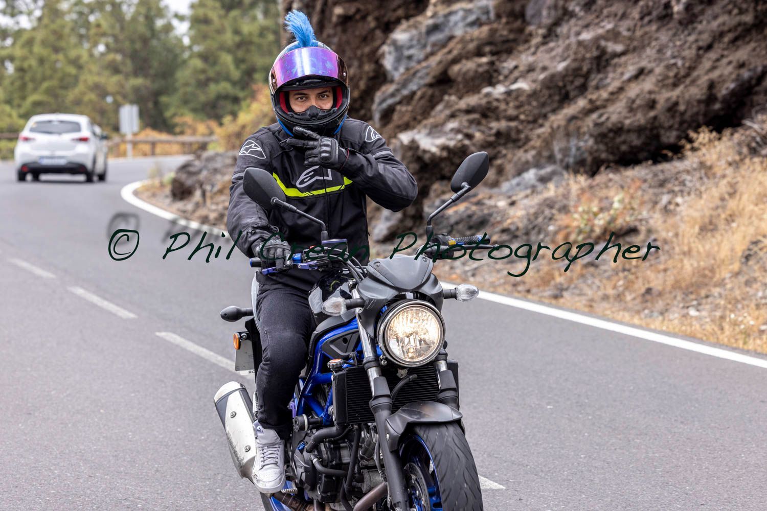 A man is riding a motorcycle down a road.