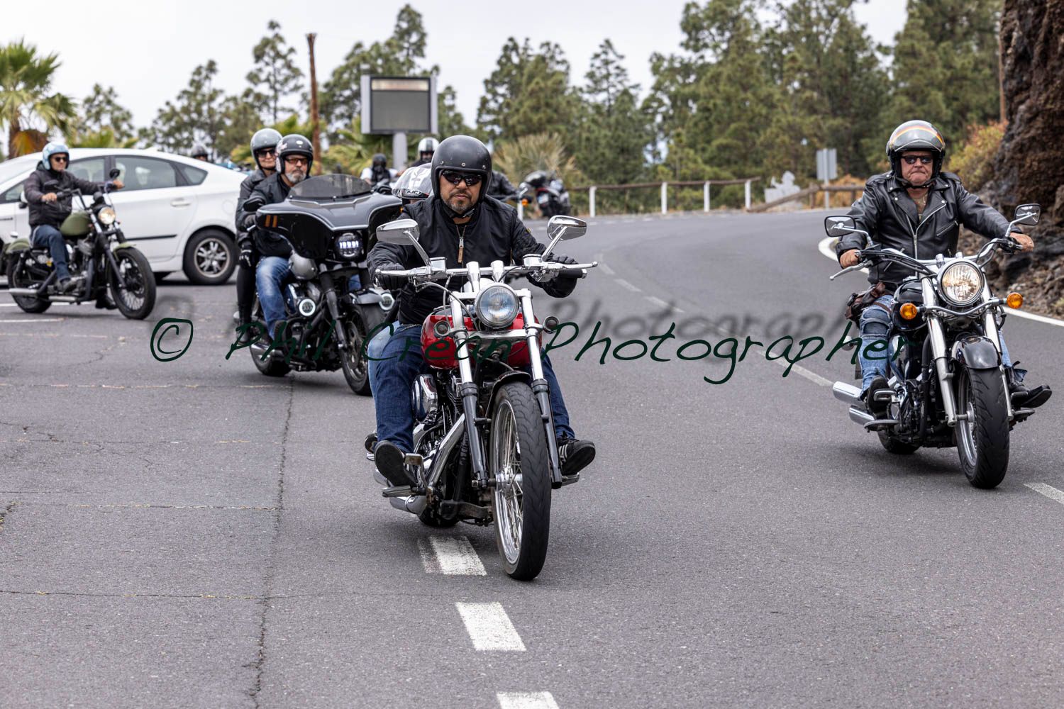 A group of men are riding motorcycles down a road