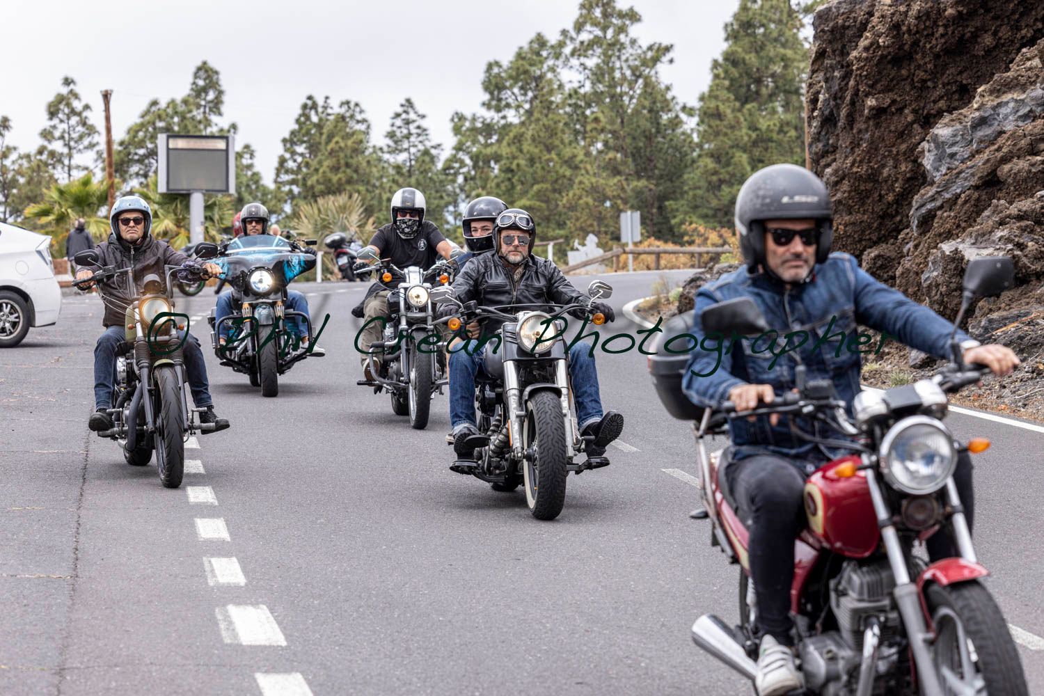 A group of men are riding motorcycles down a road.