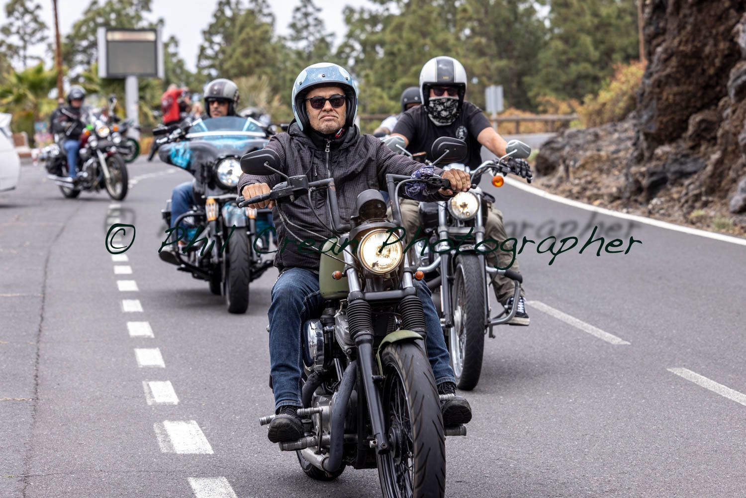 A group of people are riding motorcycles down a road.