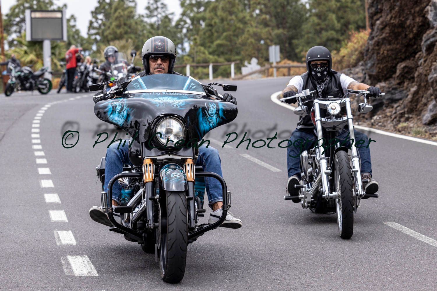 Two men are riding motorcycles down a road.