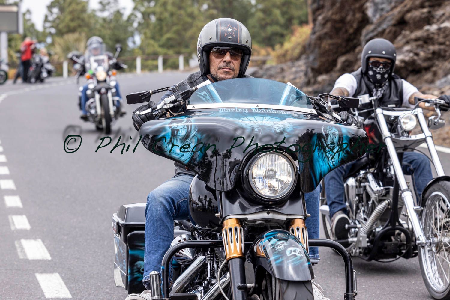 A group of men are riding motorcycles down a road.