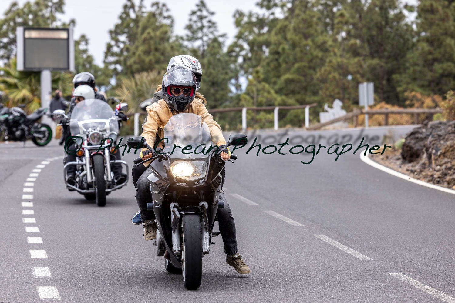 A group of people are riding motorcycles down a road.