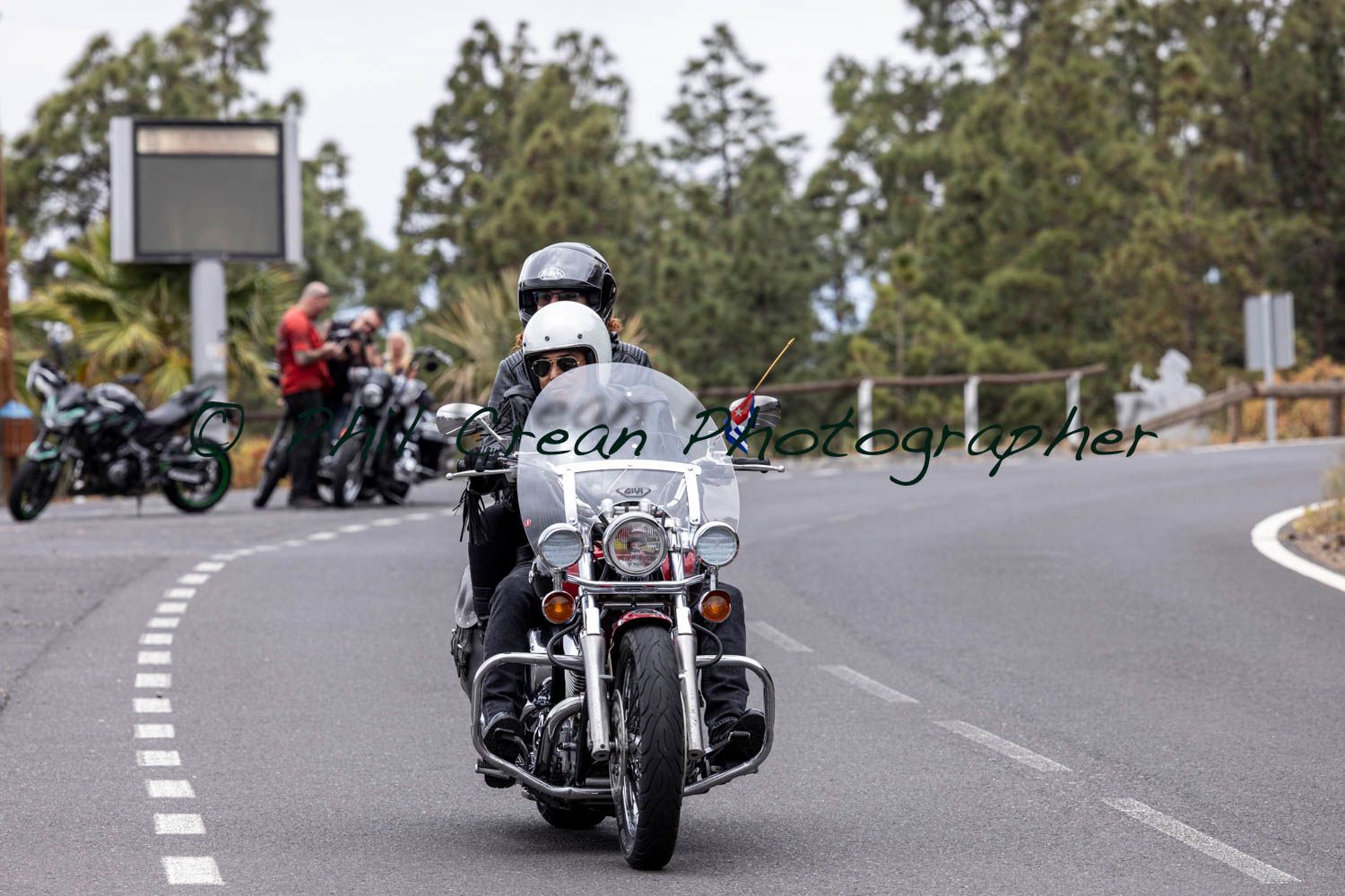 A man is riding a motorcycle down a road.