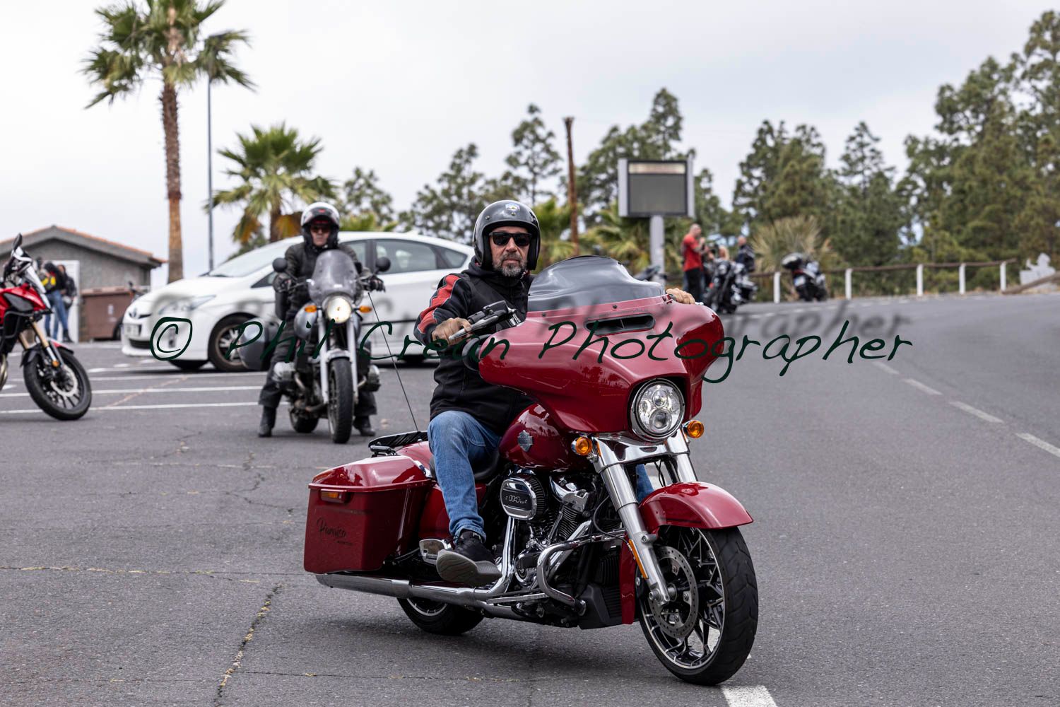 A man is riding a red harley davidson motorcycle