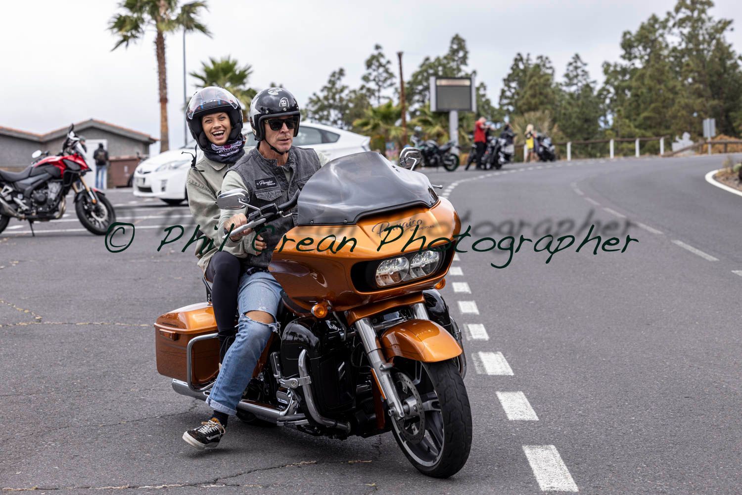 A man and a woman are riding a motorcycle down a road.