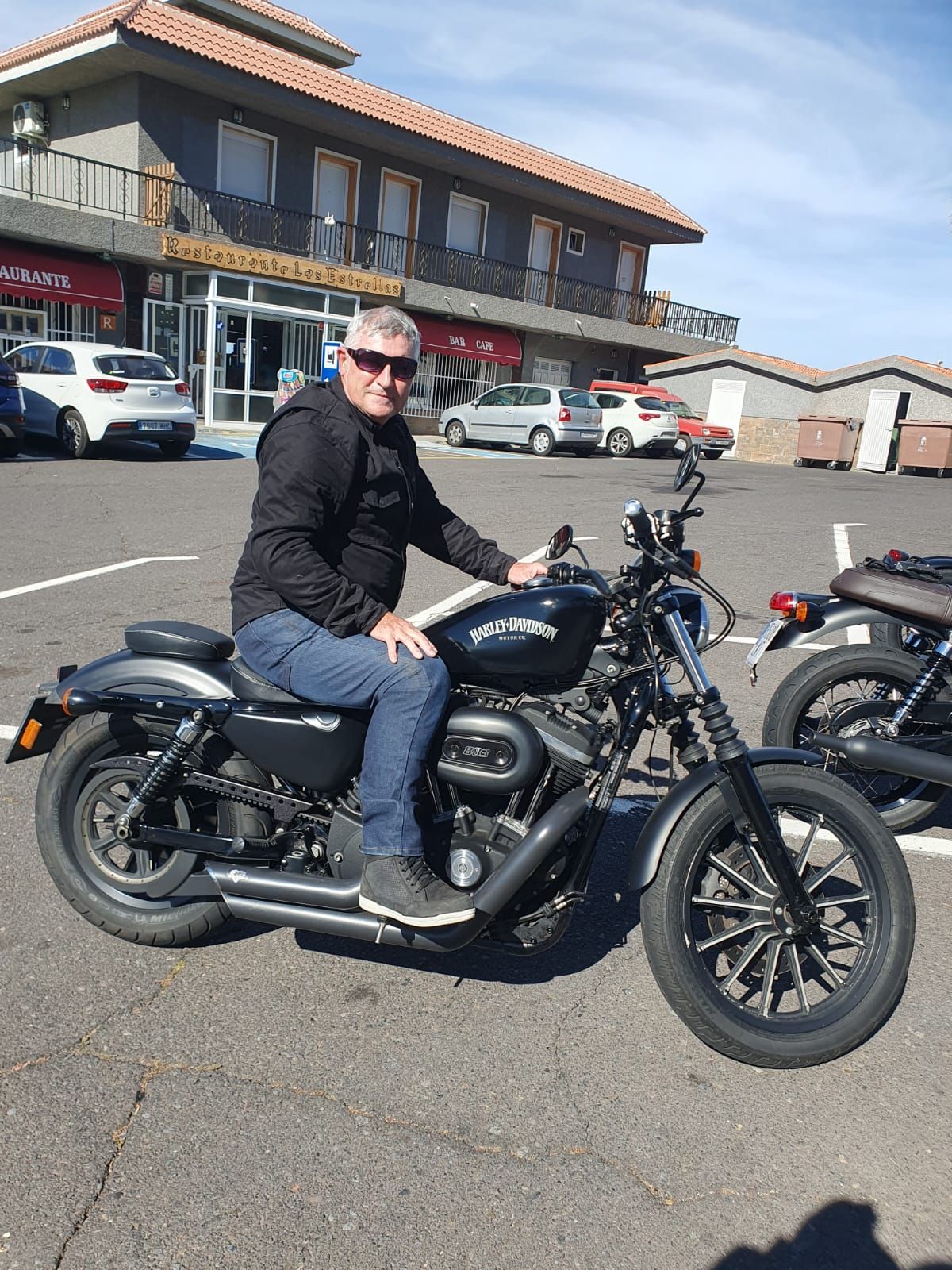 A man is sitting on a motorcycle in a parking lot.