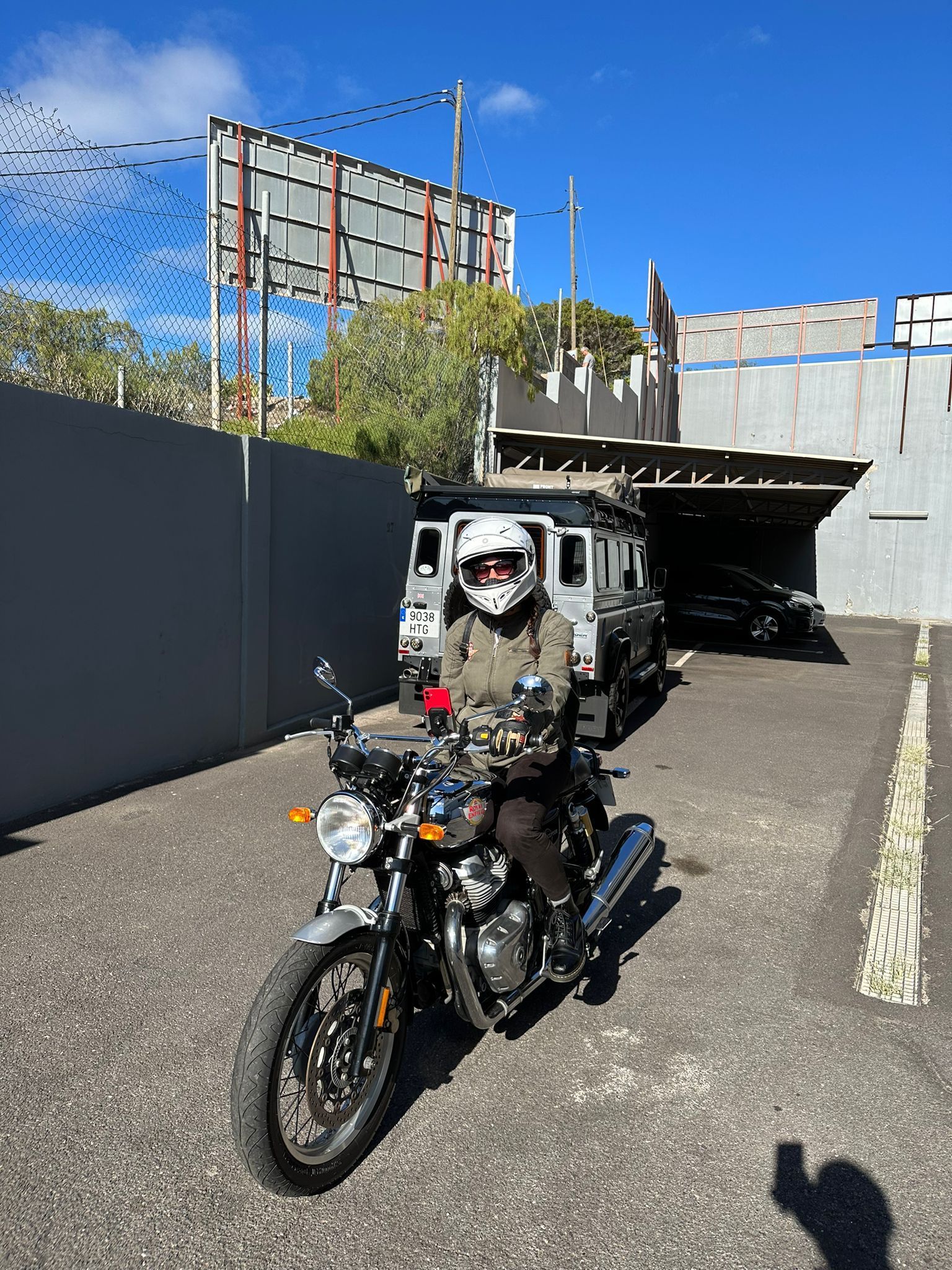 A man is riding a motorcycle in a parking lot.