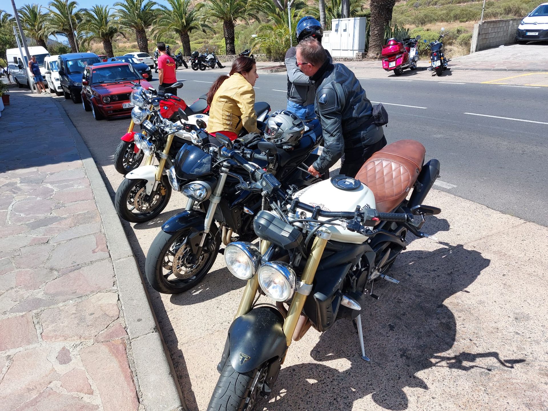 A group of people are sitting on motorcycles on the side of the road.