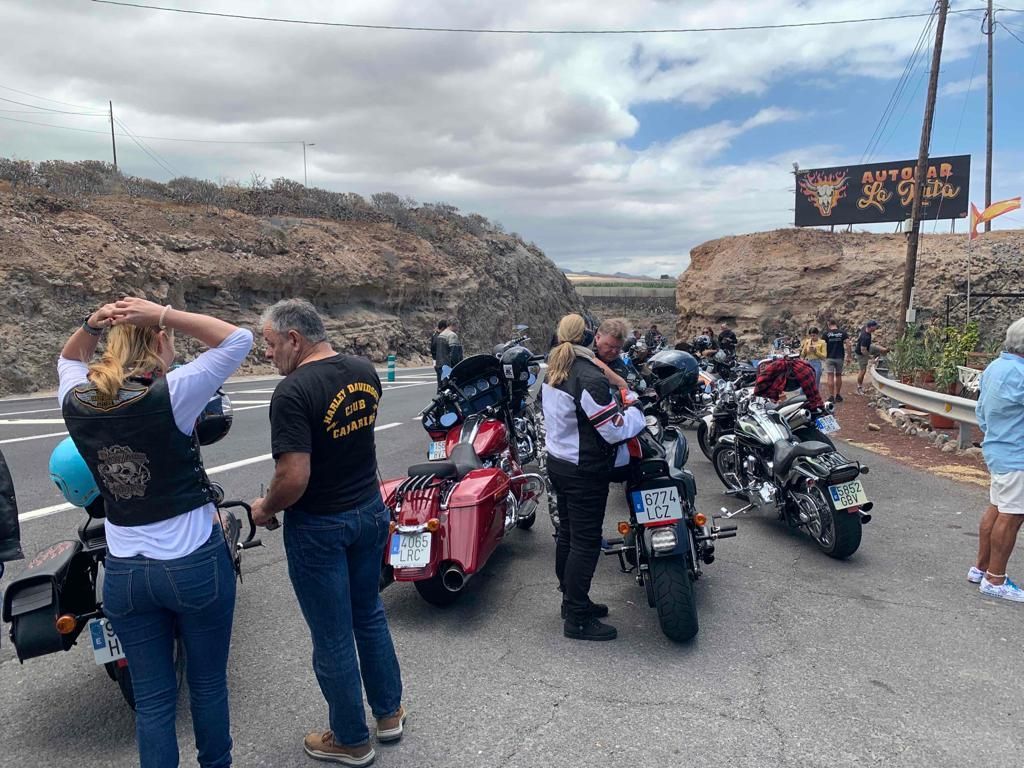 A group of people standing next to motorcycles on the side of a road.