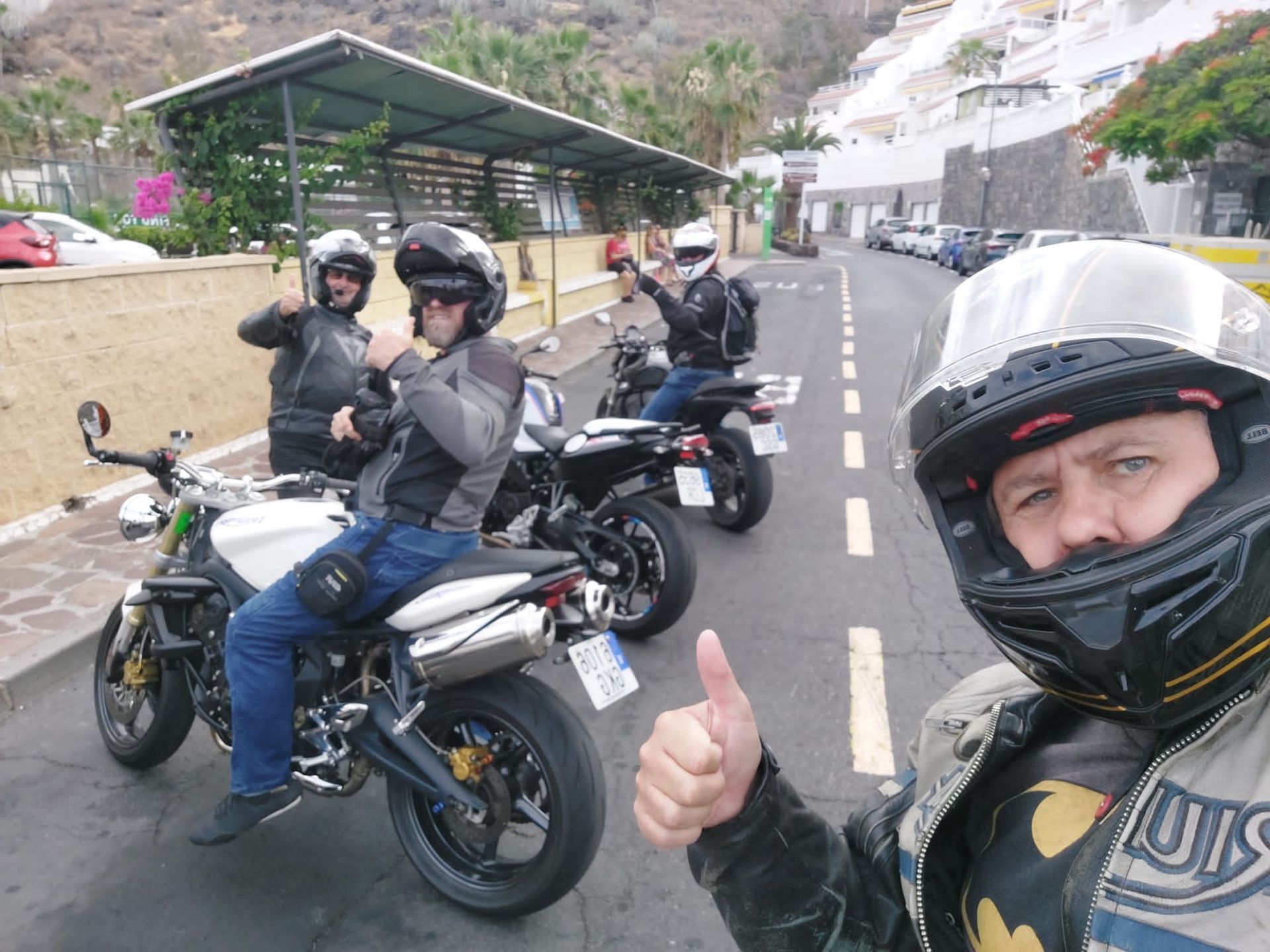 A man wearing a helmet is giving a thumbs up while riding a motorcycle