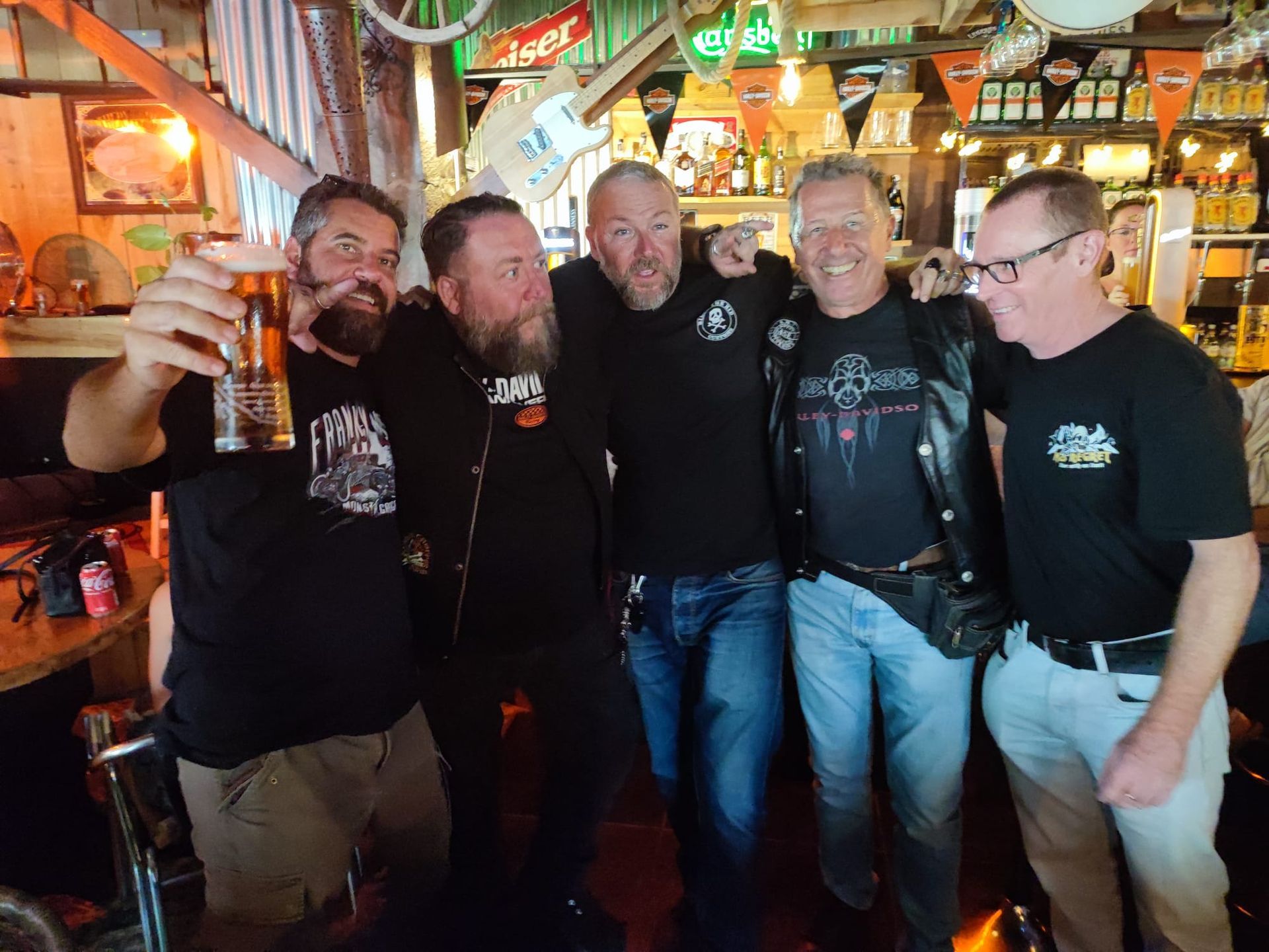 A group of men are posing for a picture in a bar.