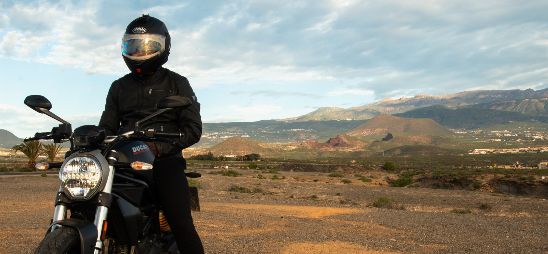 A man is standing next to a motorcycle in the desert.