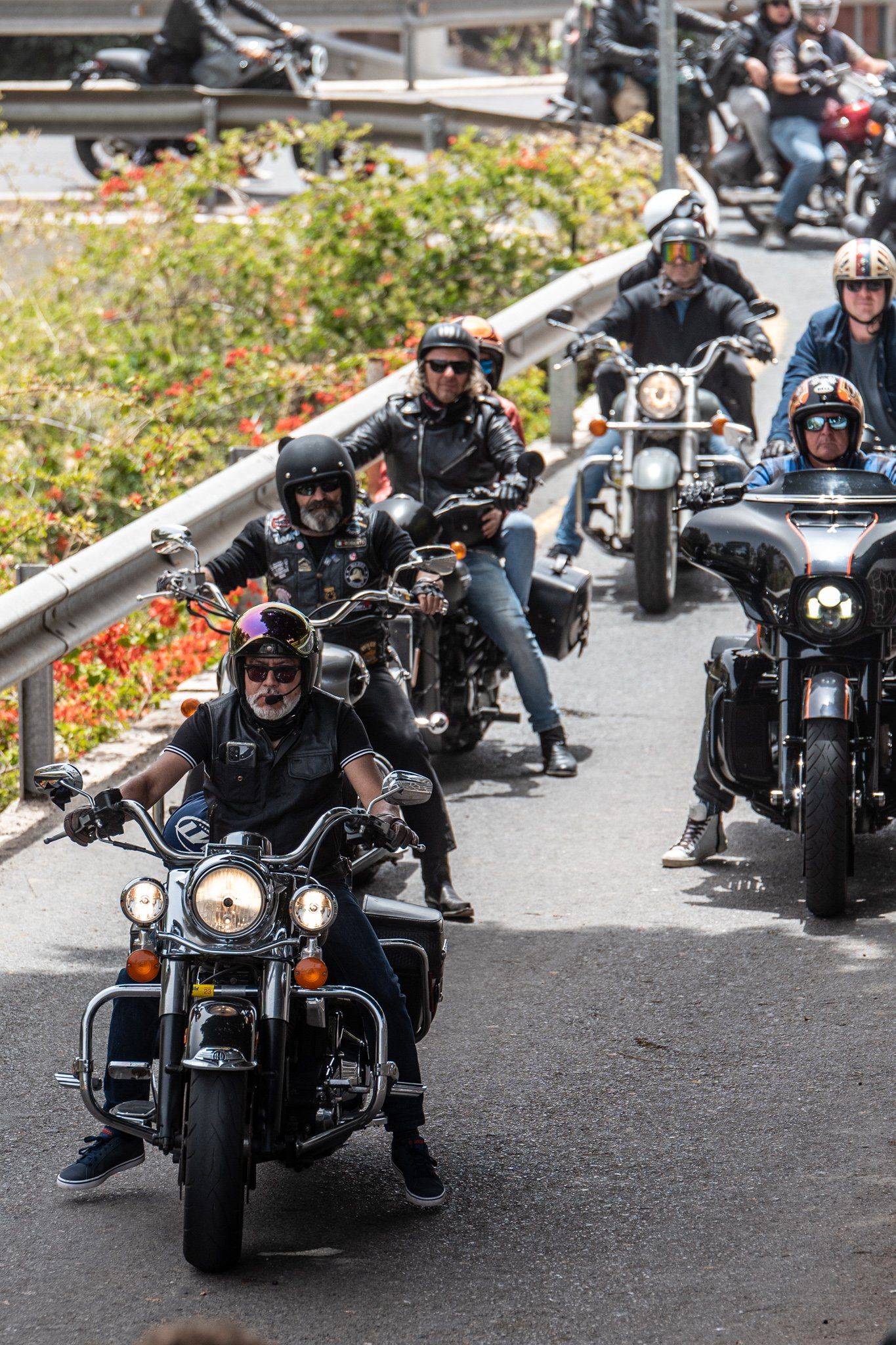 A group of men are riding motorcycles down a street.