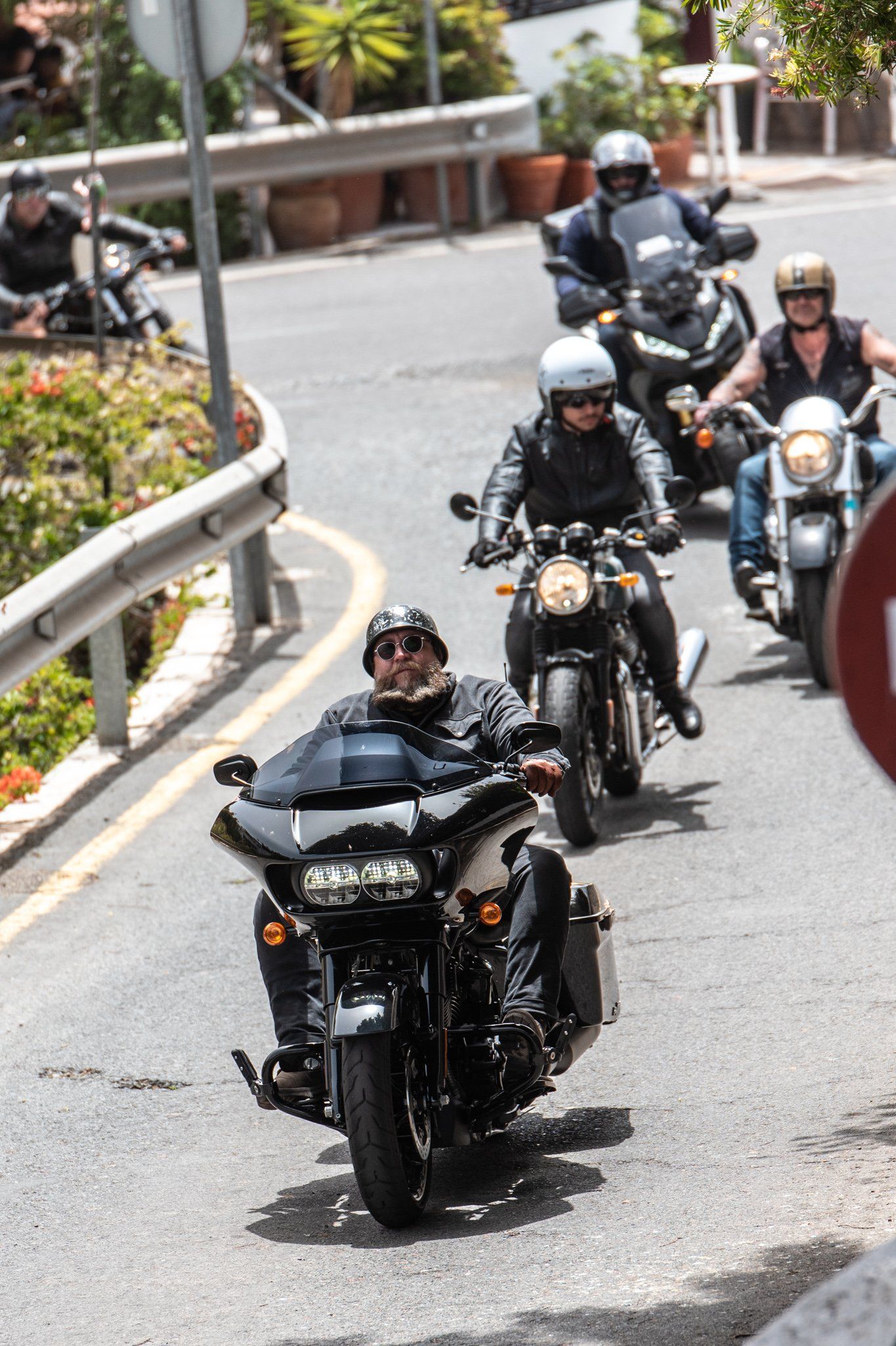 A group of people are riding motorcycles down a street