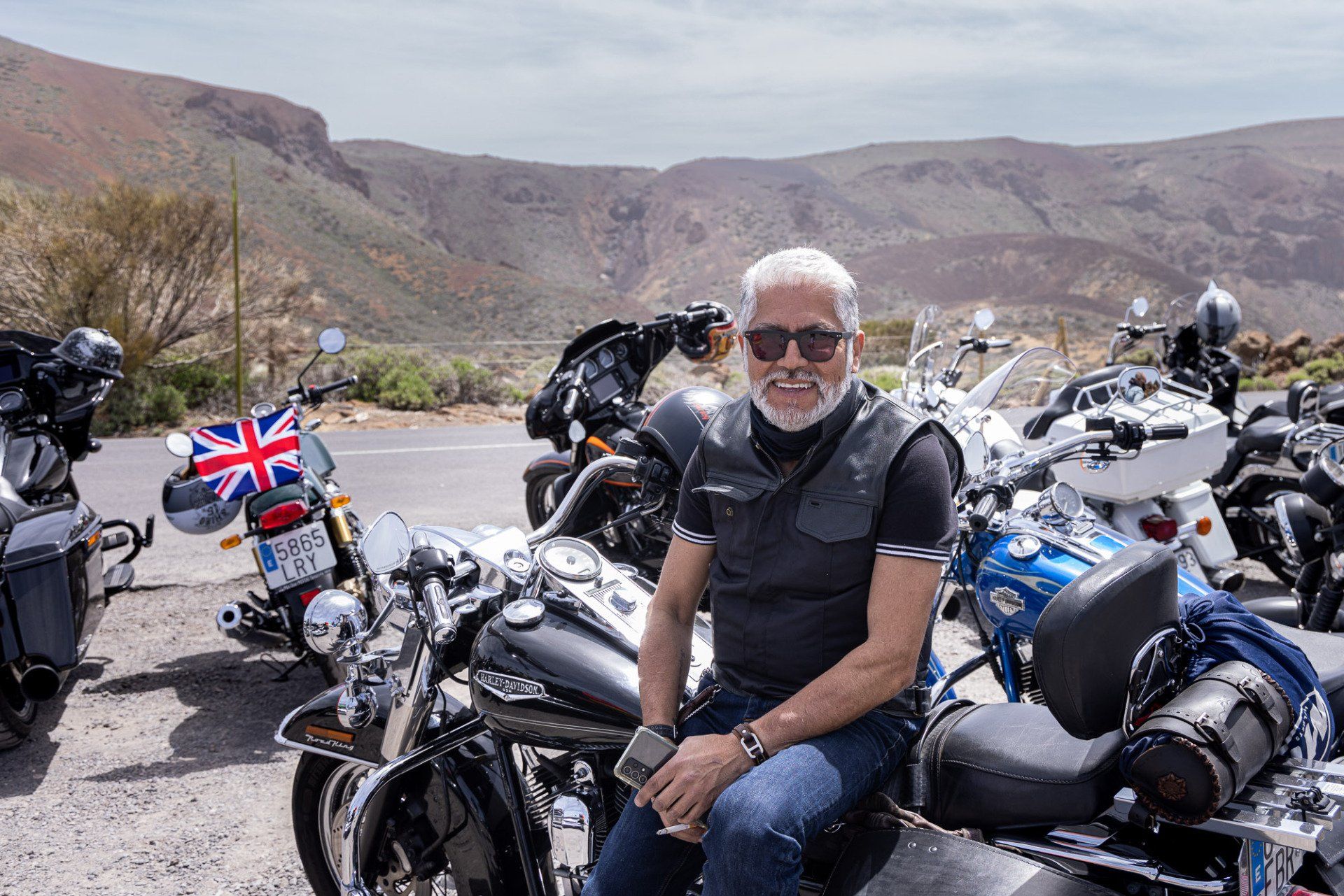 A man is sitting on a motorcycle in front of a row of motorcycles.