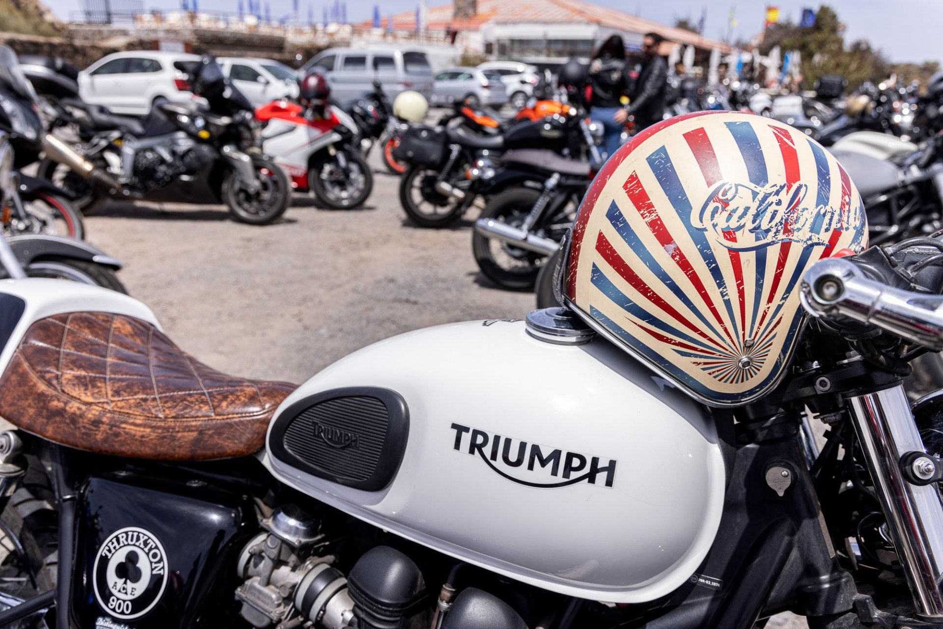 A triumph motorcycle is parked in a parking lot with other motorcycles.