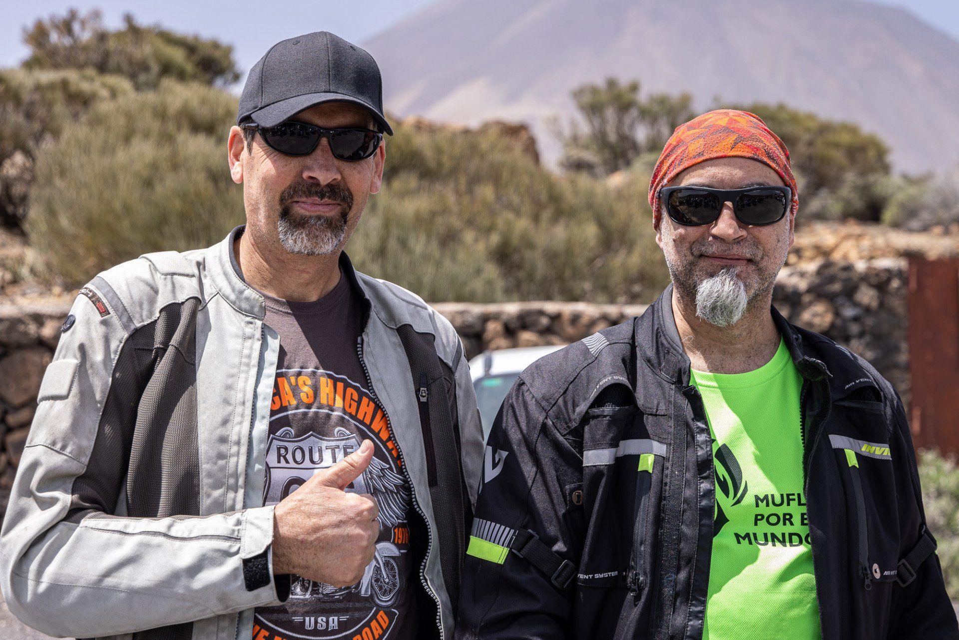 Two men are standing next to each other and one of them is giving a thumbs up.