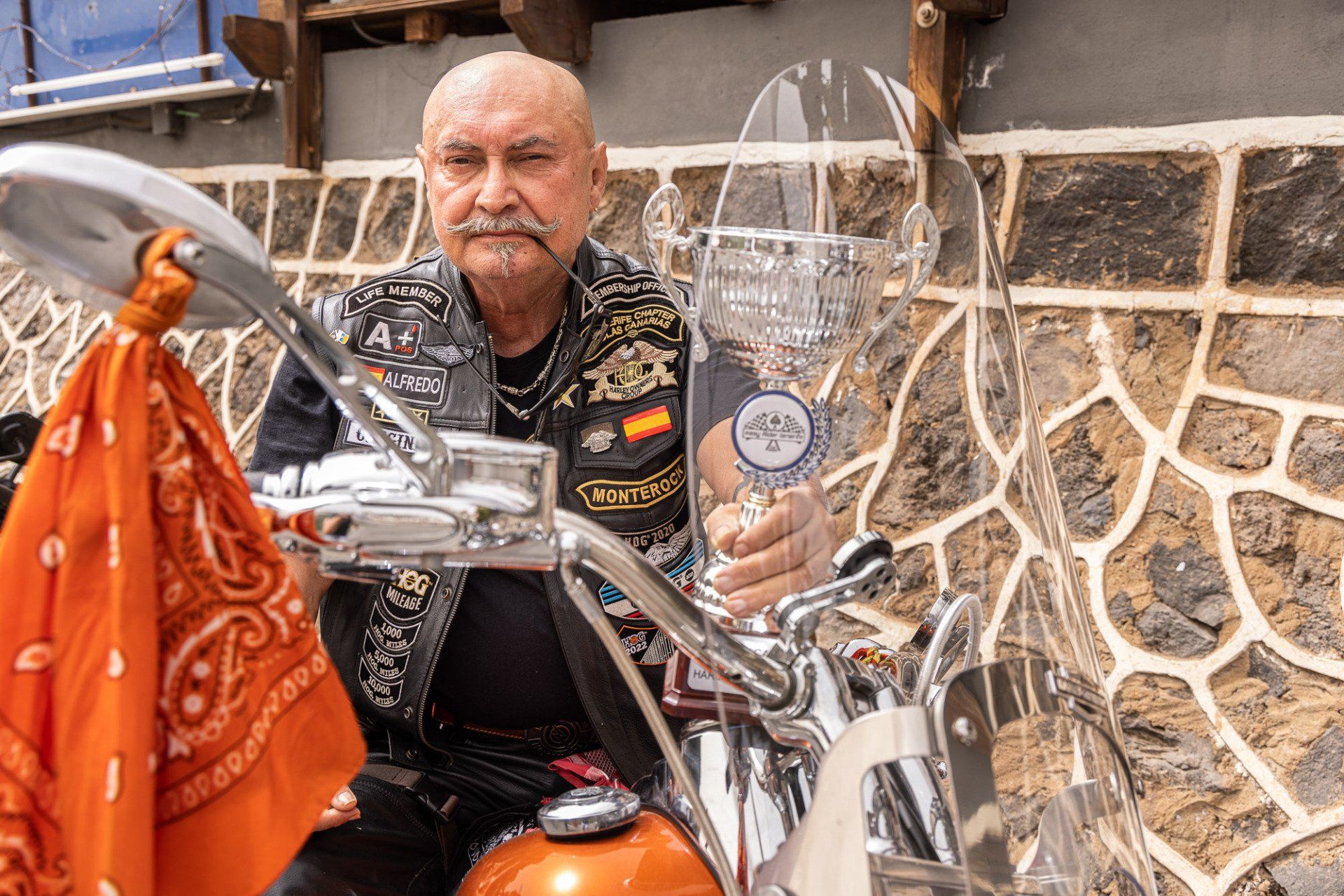 A man is sitting on a motorcycle wearing an orange bandana.