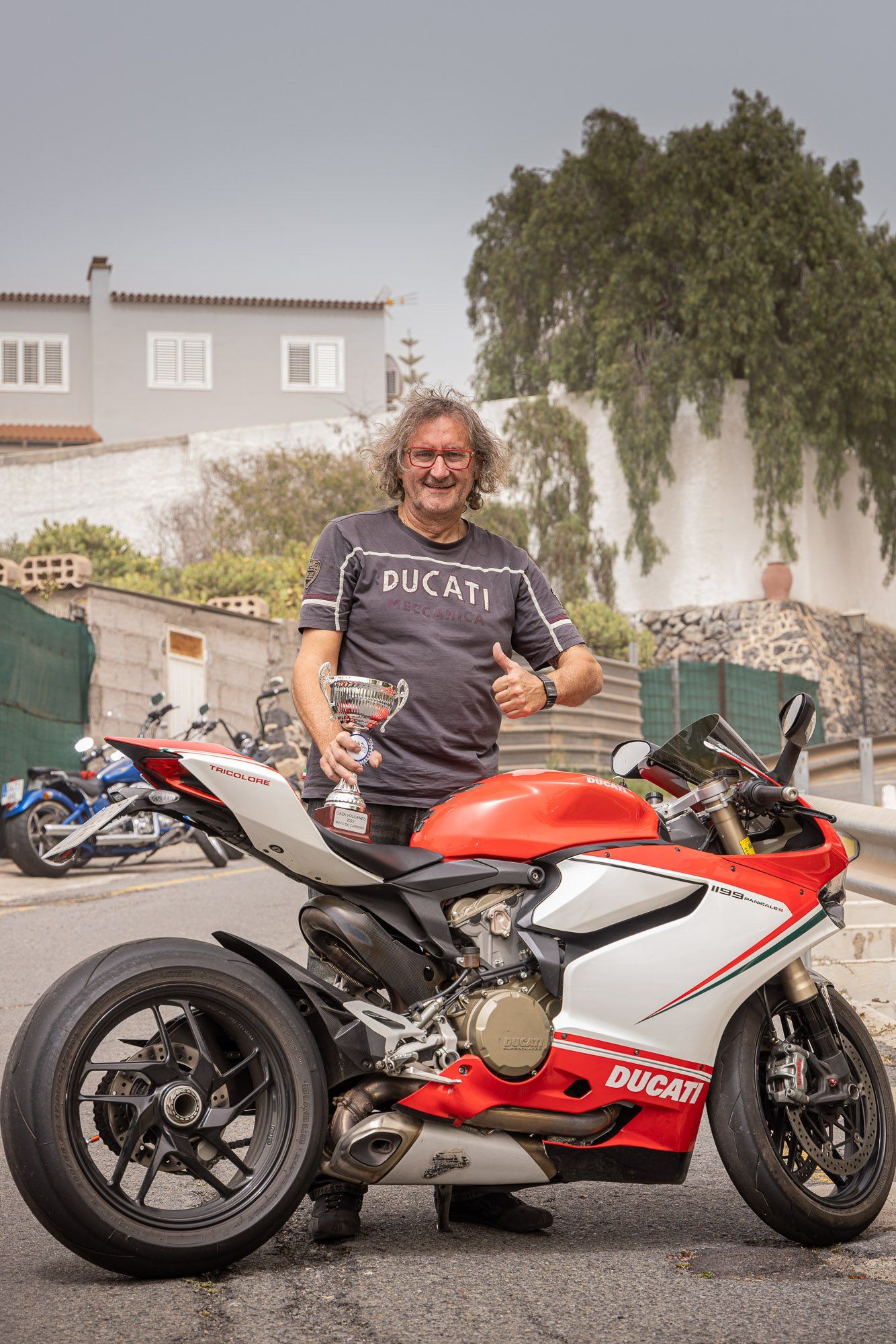 A man is standing next to a red and white motorcycle.