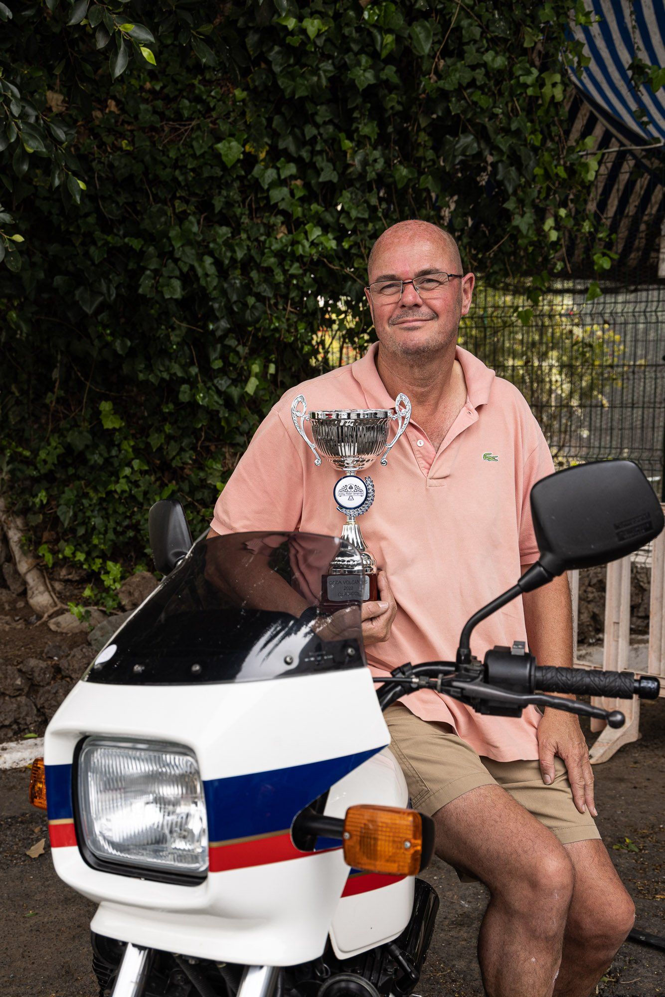 A man is sitting on a motorcycle holding a trophy.