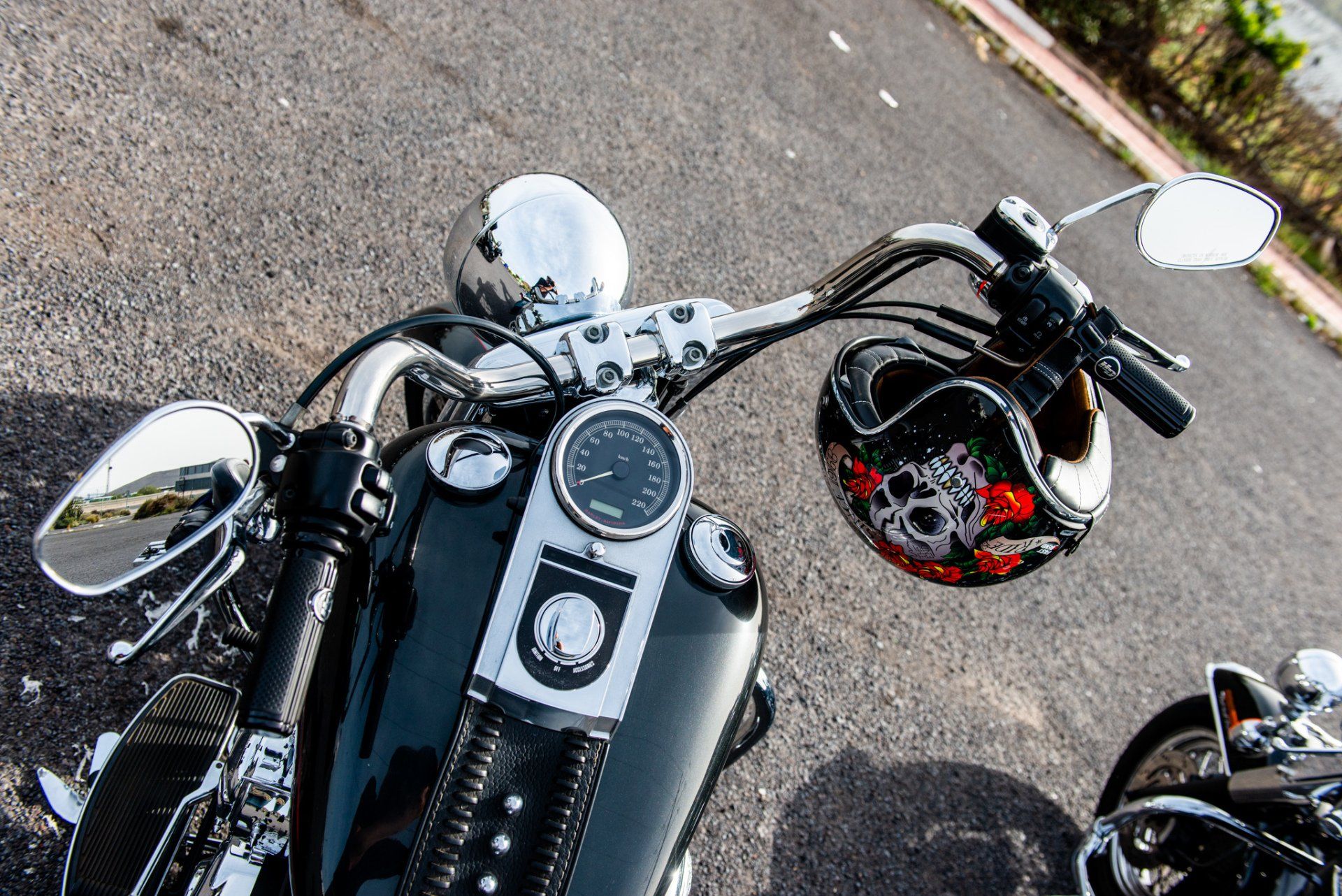 A motorcycle is parked on the side of the road next to a helmet.