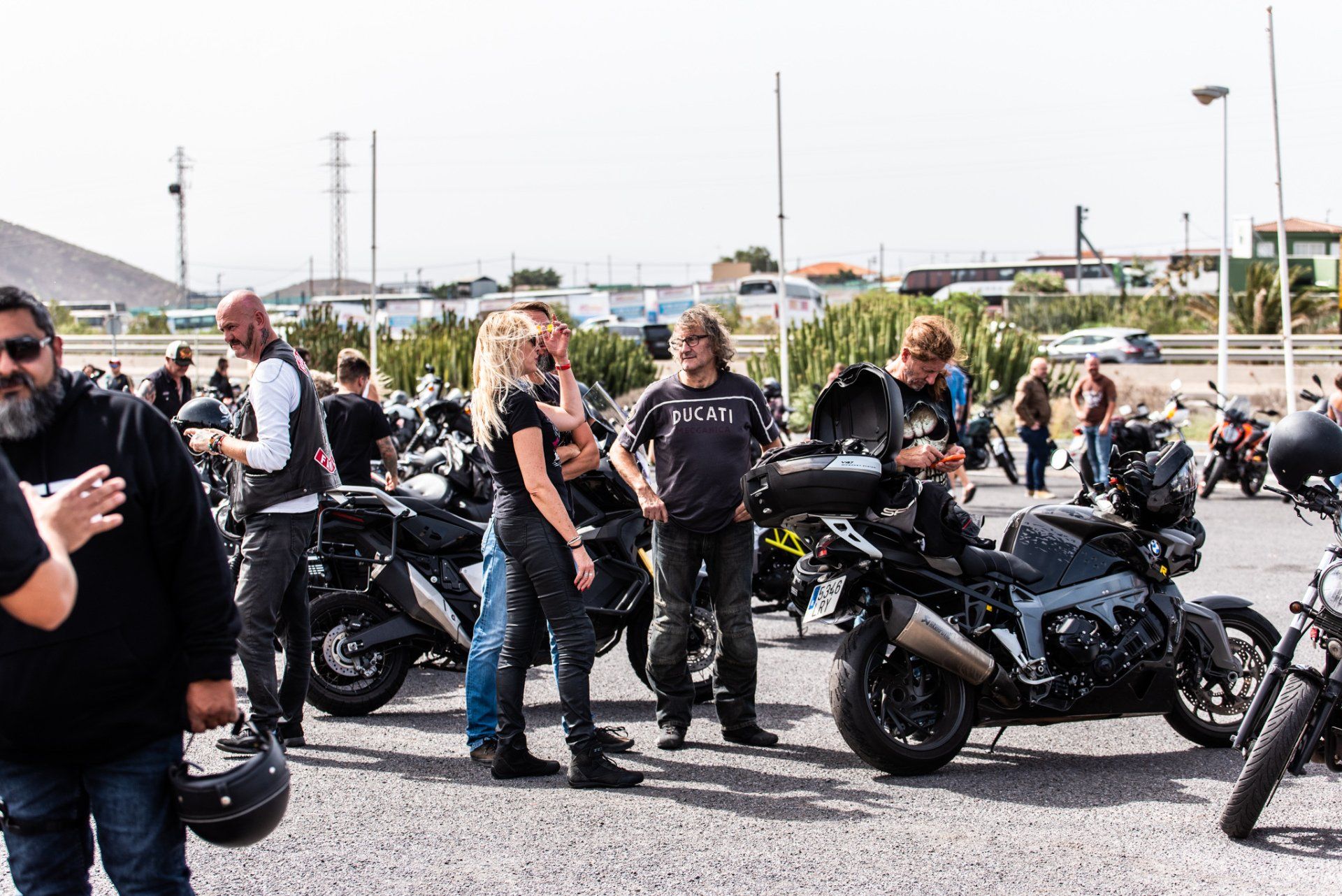 A group of people are standing next to motorcycles in a parking lot.