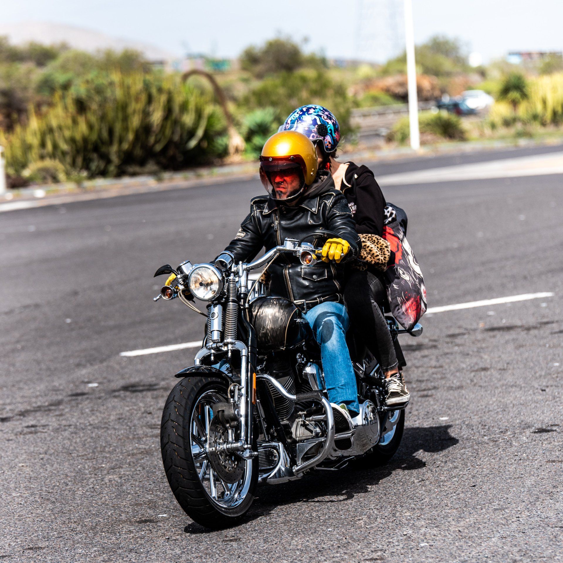 A man and woman are riding a motorcycle down a road