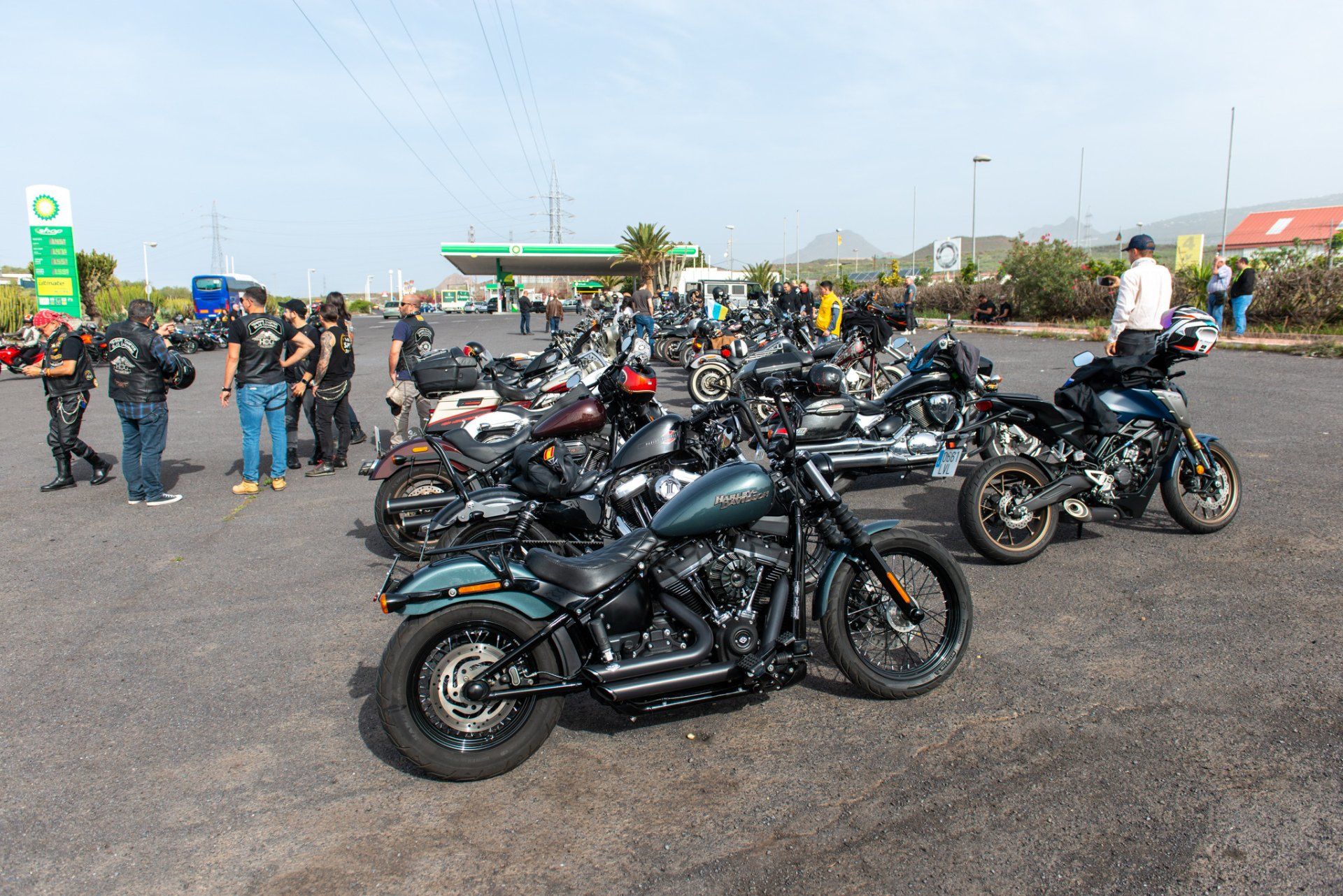 A group of motorcycles are parked in a parking lot in front of a gas station.