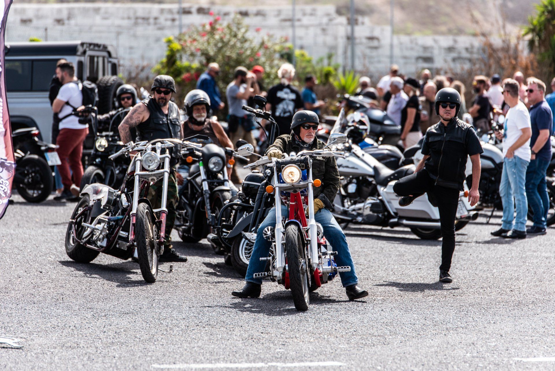A group of people are standing around motorcycles in a parking lot.