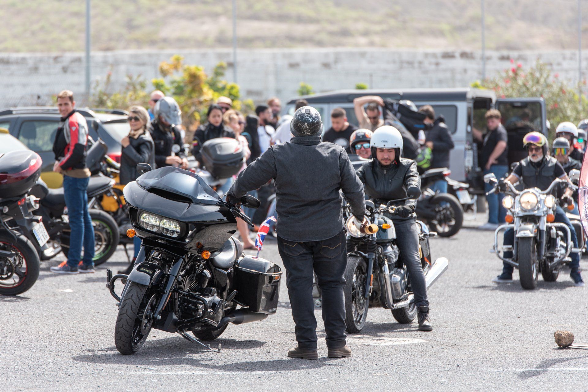 A group of motorcycle riders are standing in a parking lot.
