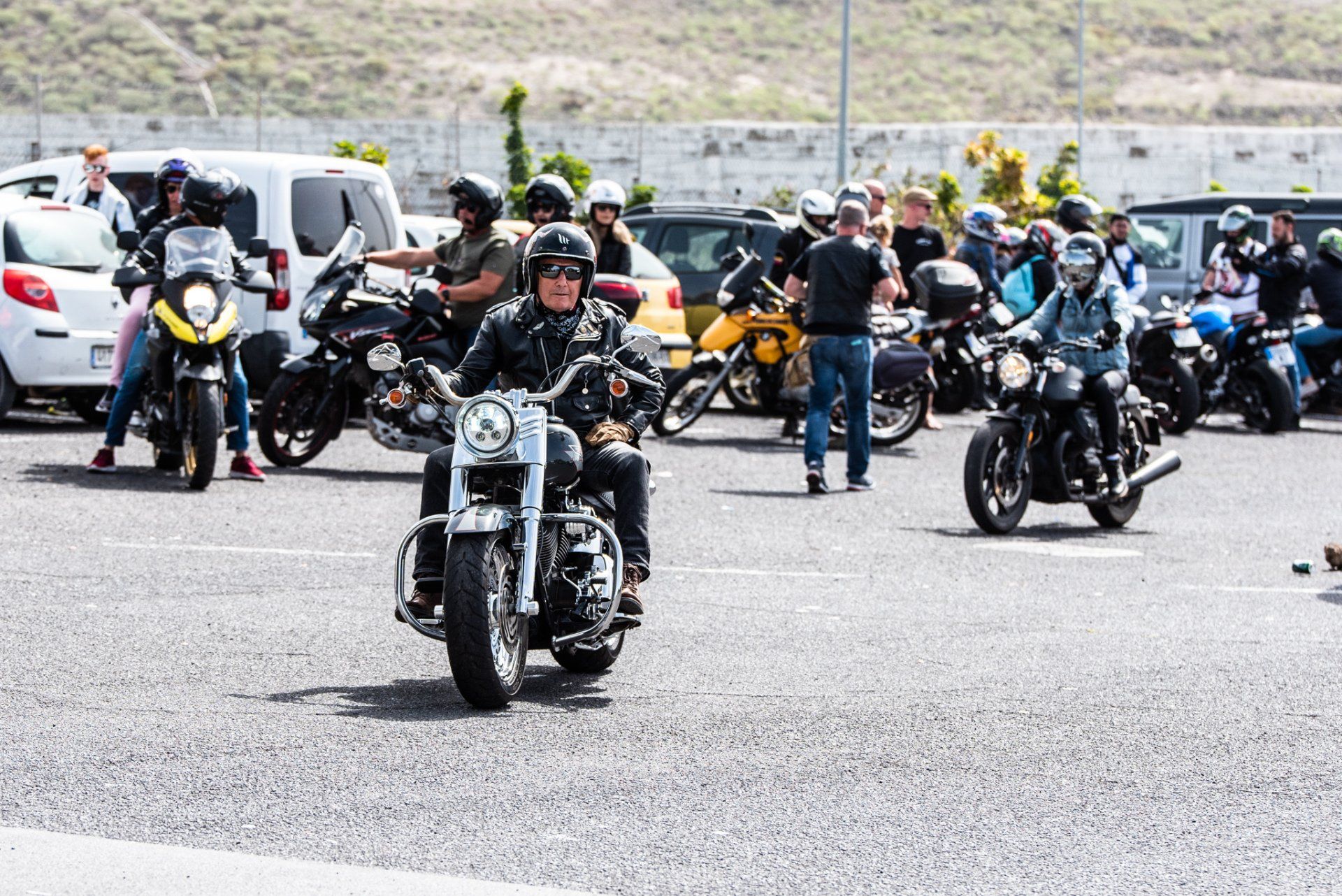 A group of people are riding motorcycles in a parking lot.