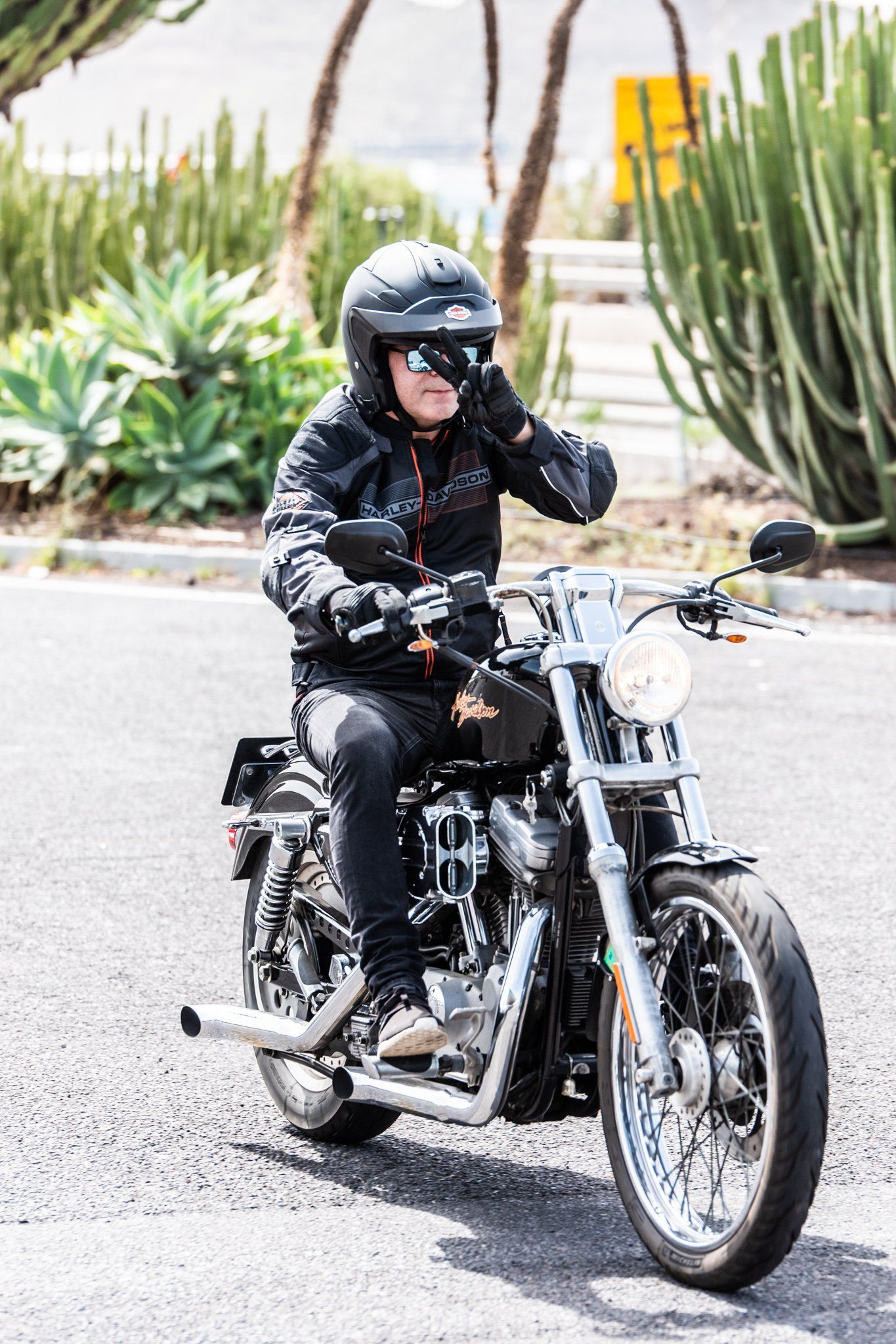 A man is riding a motorcycle down a road while talking on a cell phone.