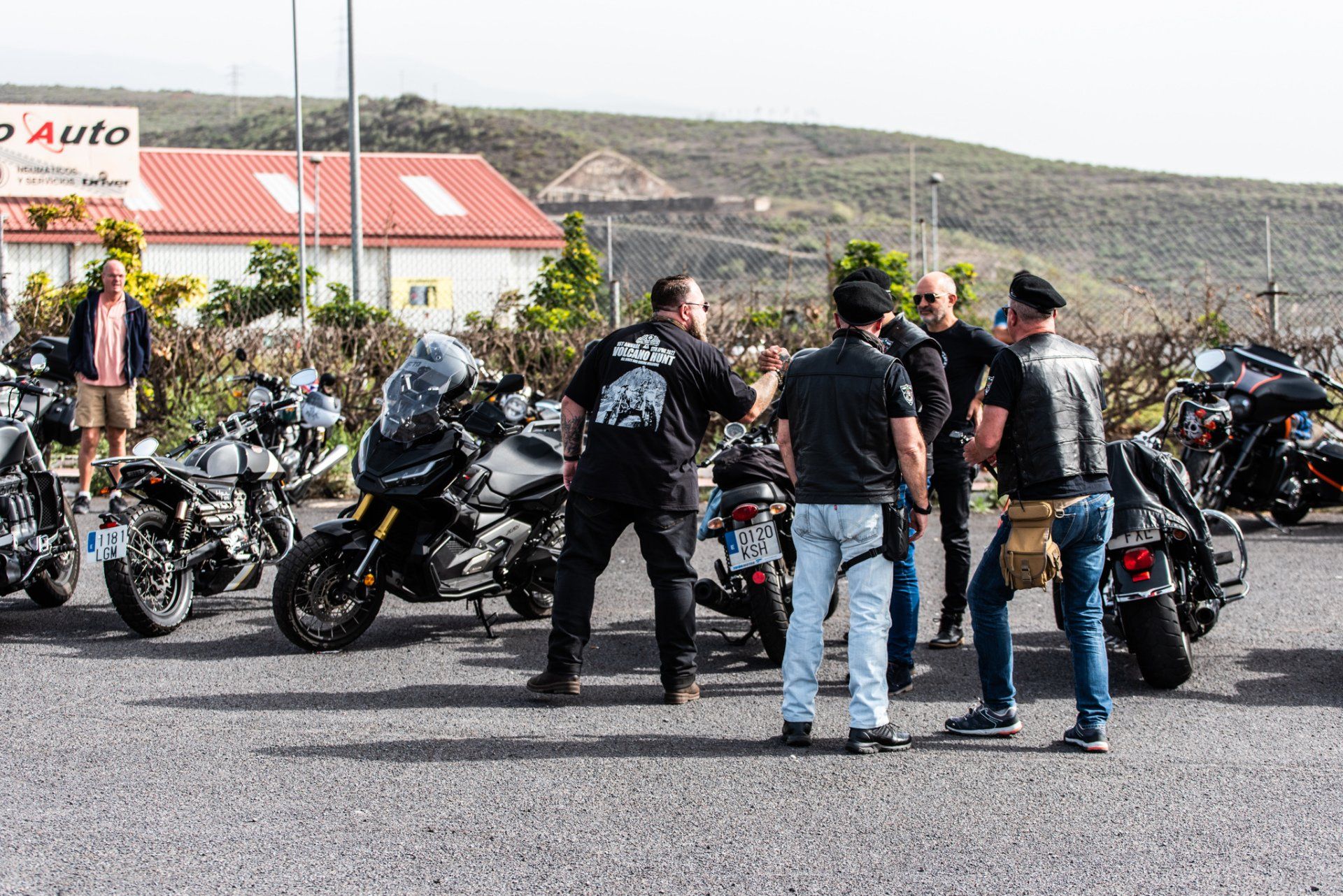 A group of men are standing next to motorcycles in a parking lot.