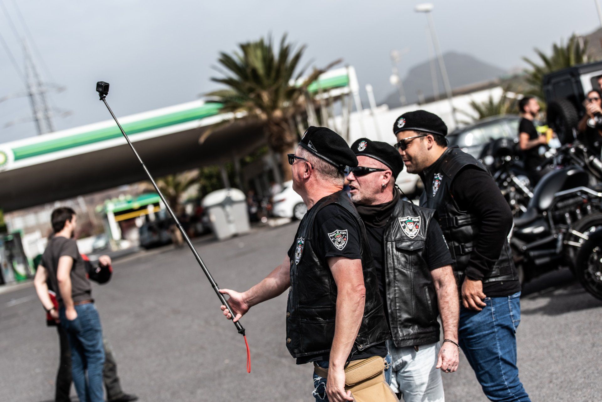 A group of men are taking a selfie in front of a gas station.