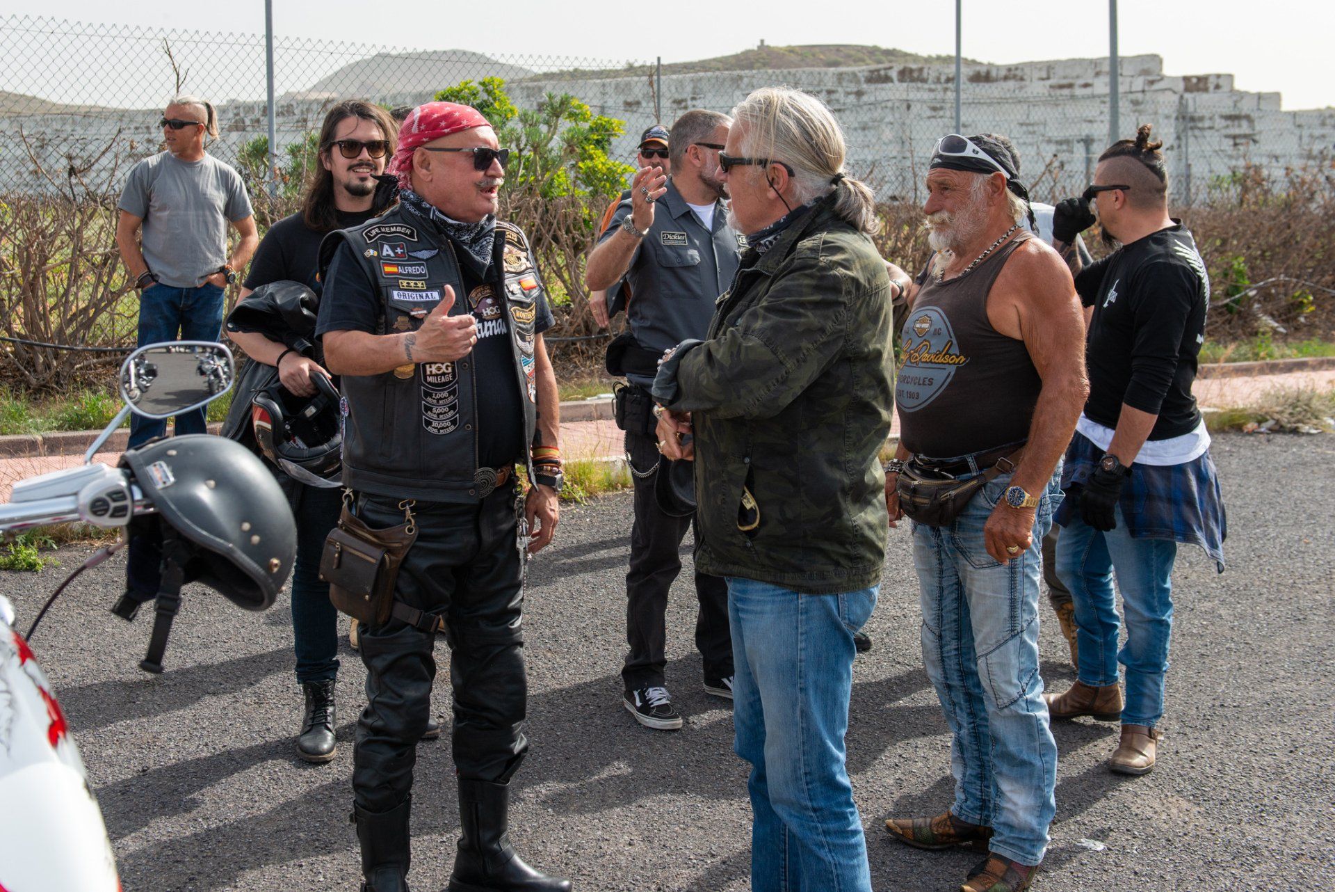A group of men are standing in a parking lot talking to each other.