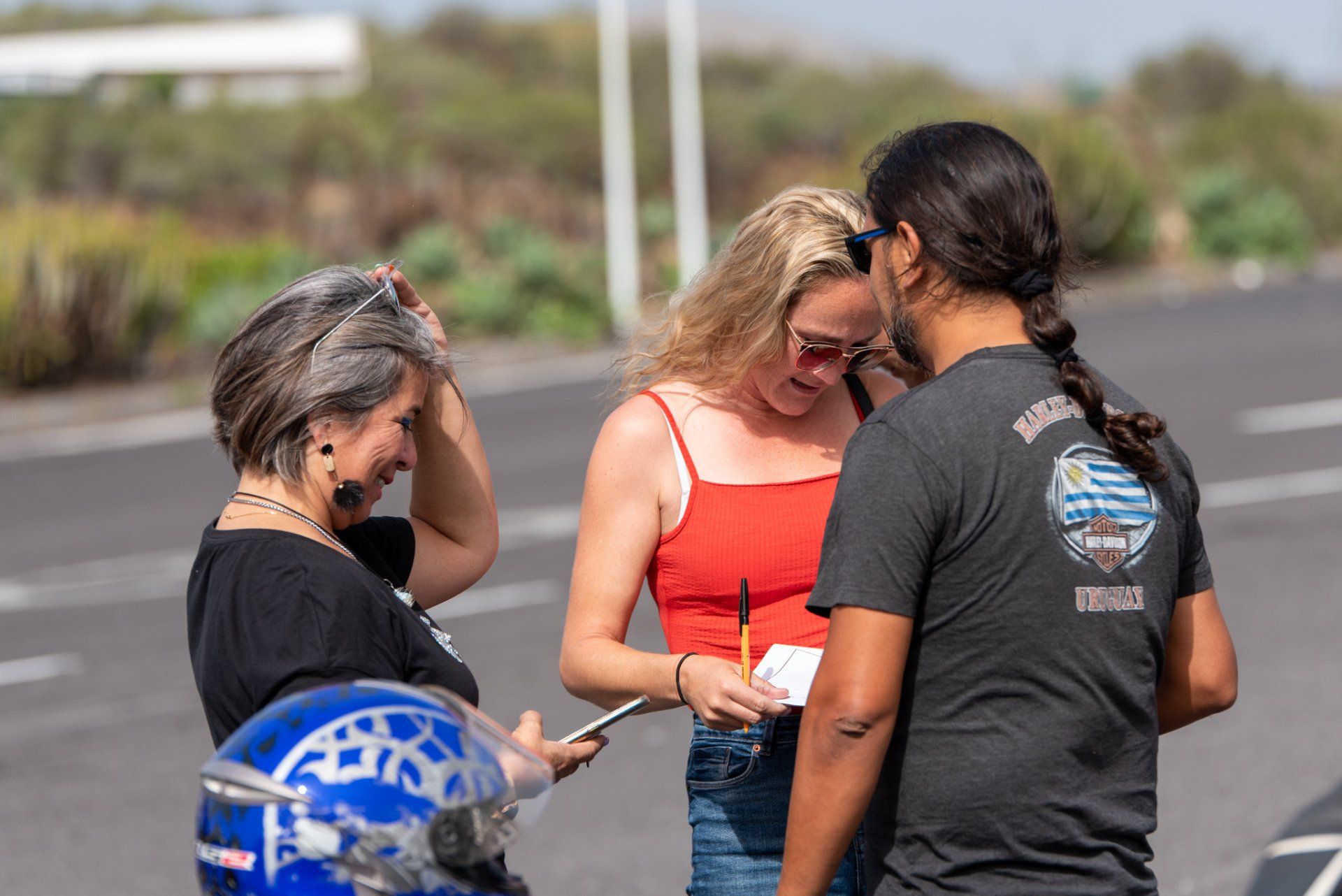 A group of people are standing on the side of the road talking to each other.