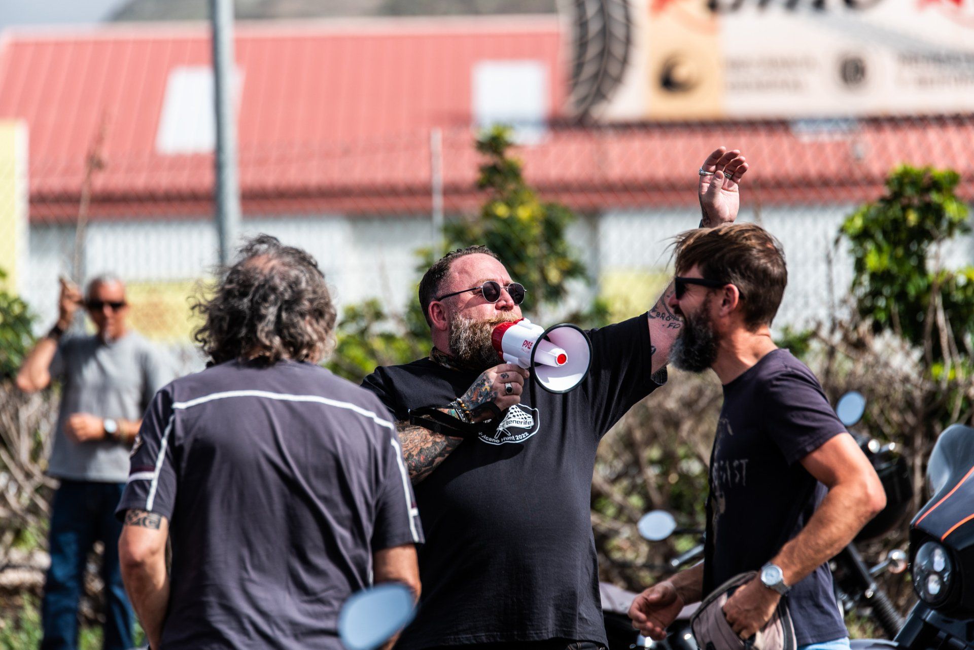 A man with a beard is holding a megaphone and talking to two other men.