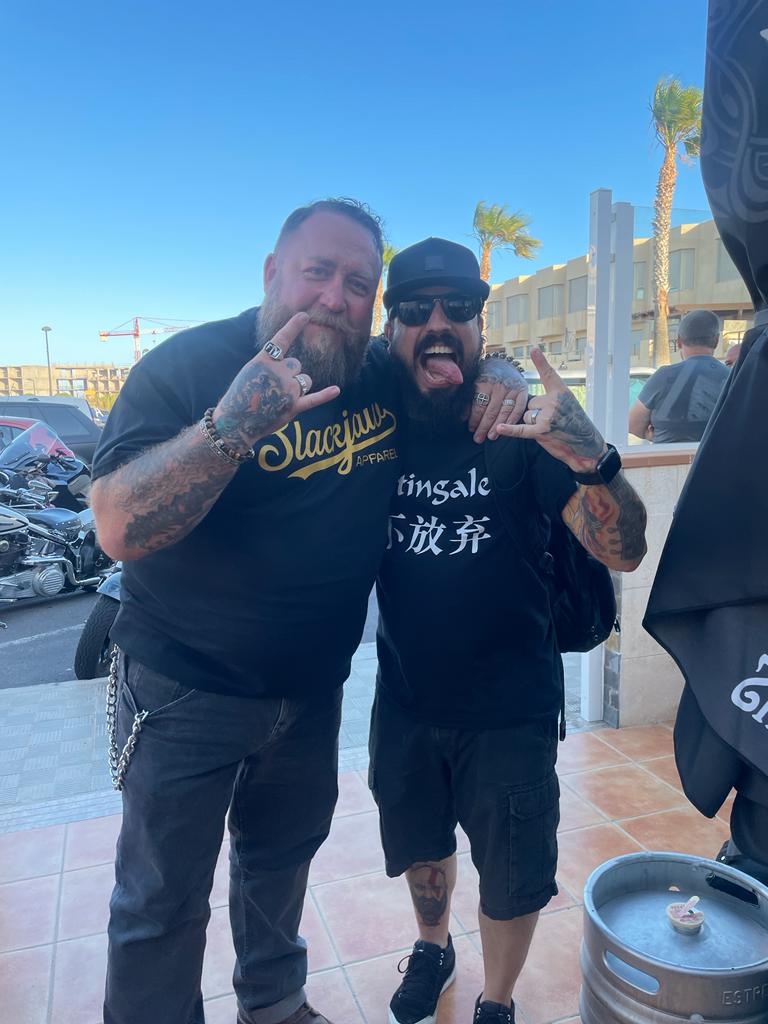 Two men are posing for a picture and one of them is wearing a shirt that says ' slayer ' on it